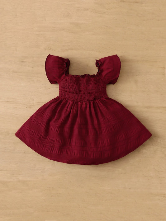 Prenda burdeos vestido para bebe detalle de la falda amplia y acabado texturizado