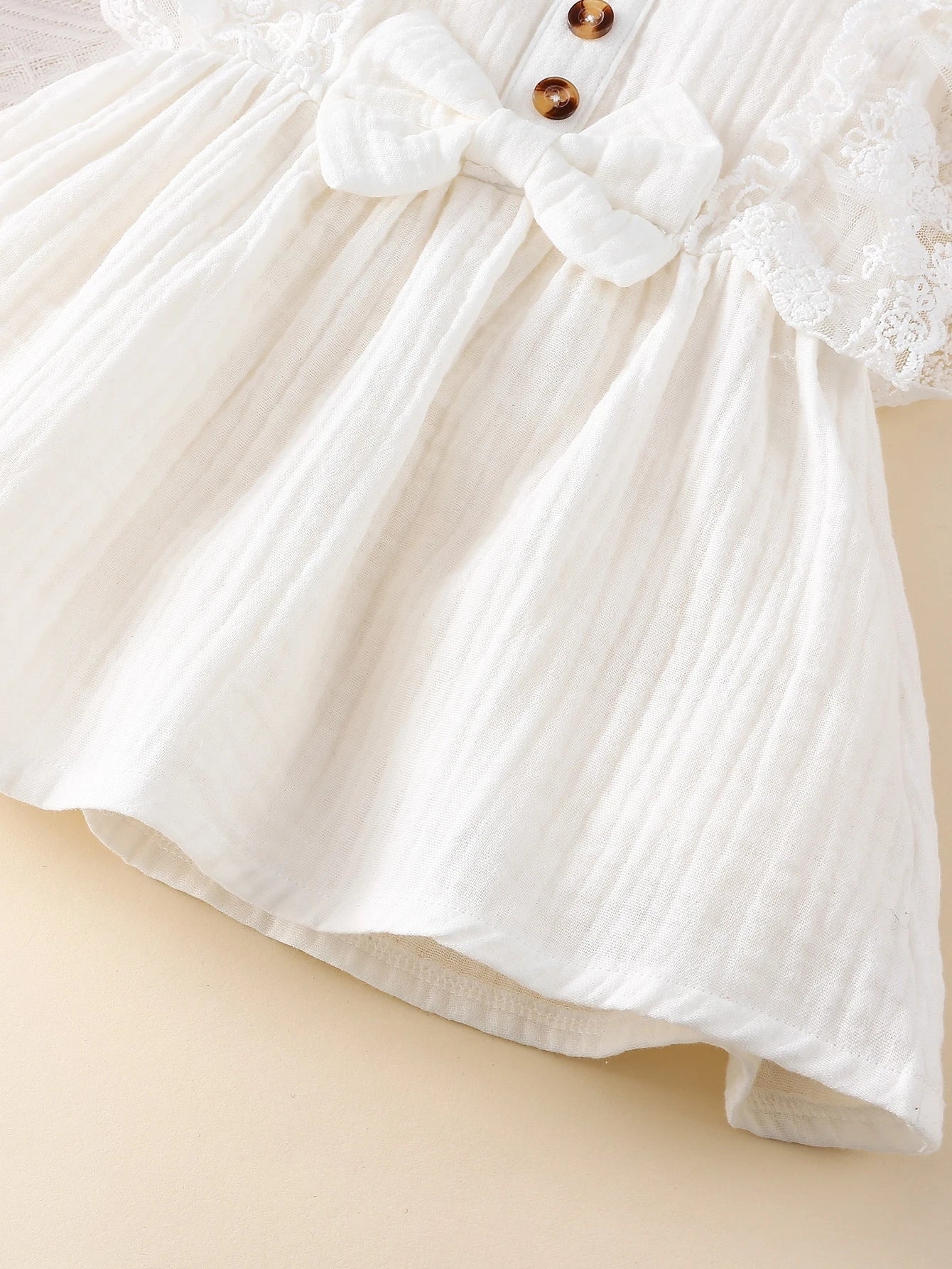 Prenda blanca vestido para bebe con lazo y botones vista frontal