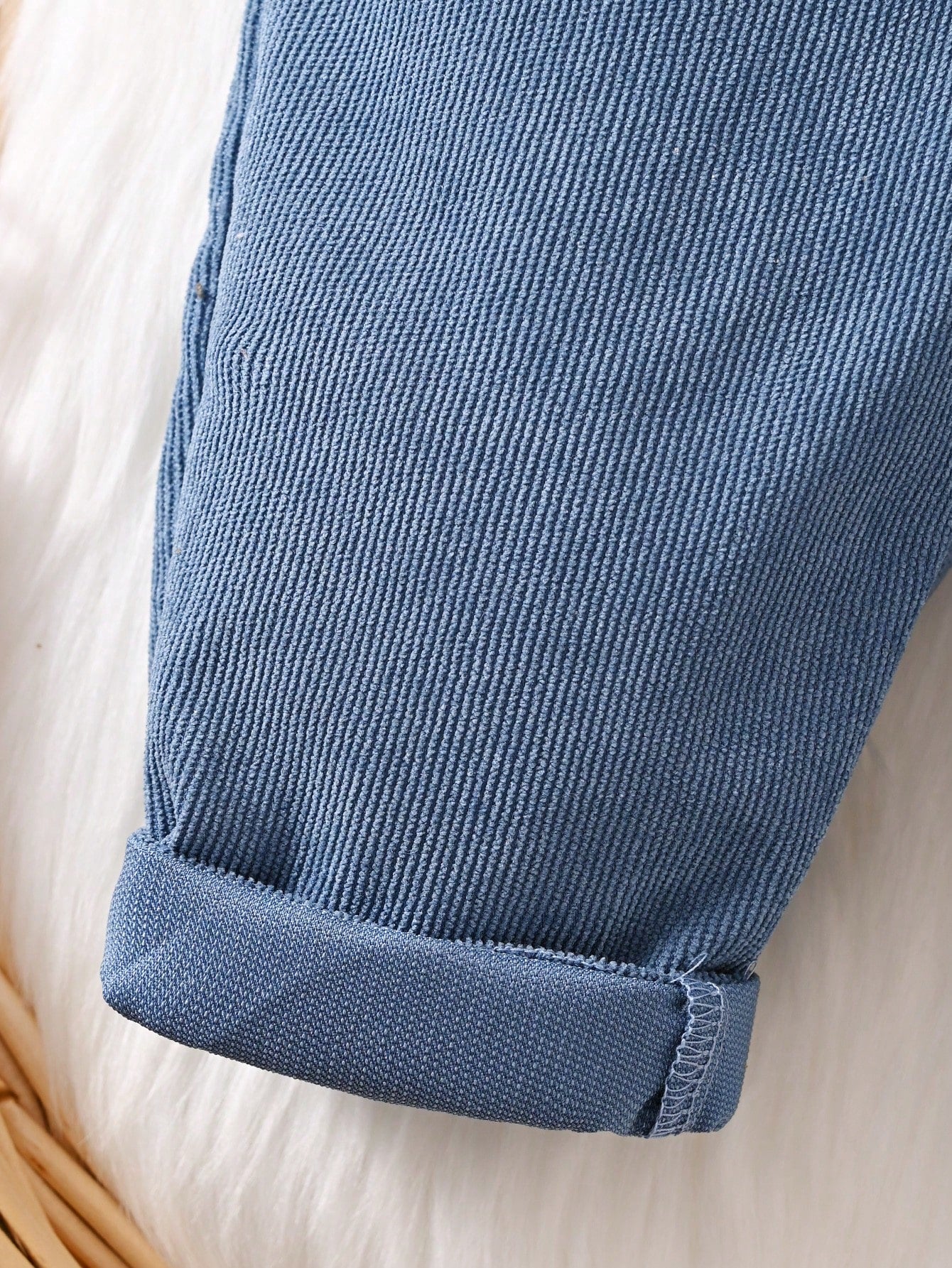 Prenda azul overol para bebe detalle de la tela de pana y bajos doblados
