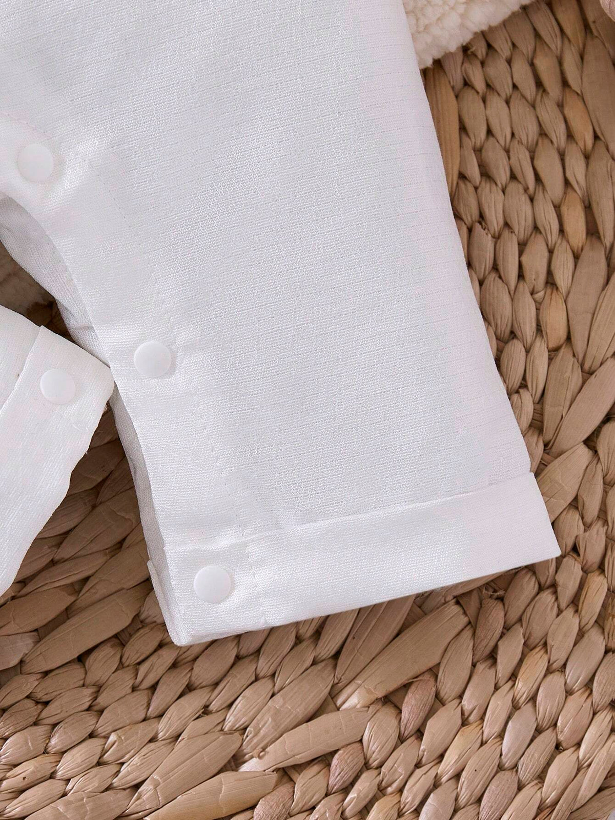 Prenda blanca enterizo para bebe detalle de botones a presión en las piernas