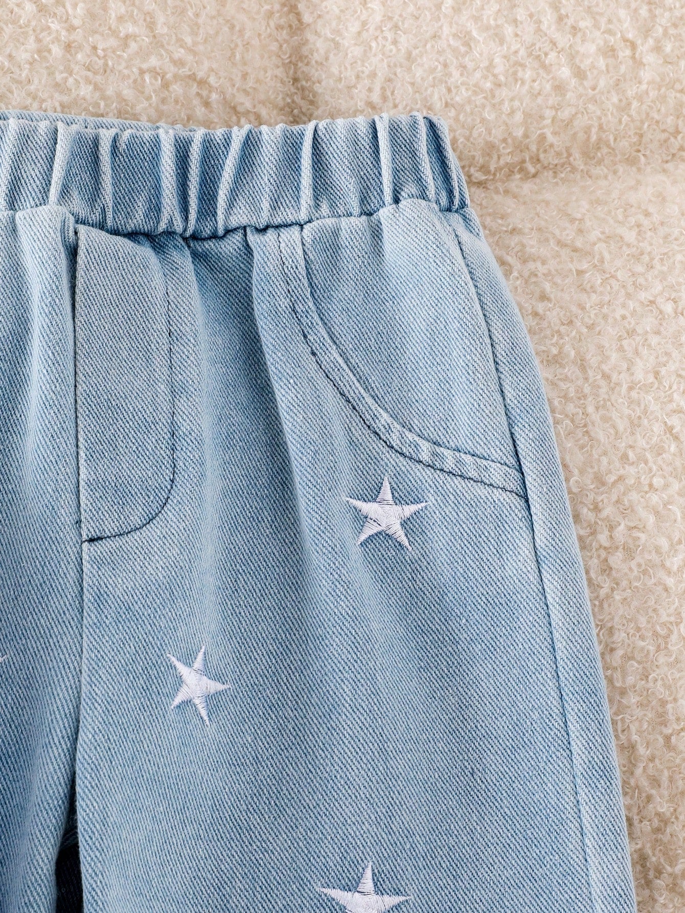 Prenda azul claro pantalon para bebe con estrellas bordadas detalle del acabado