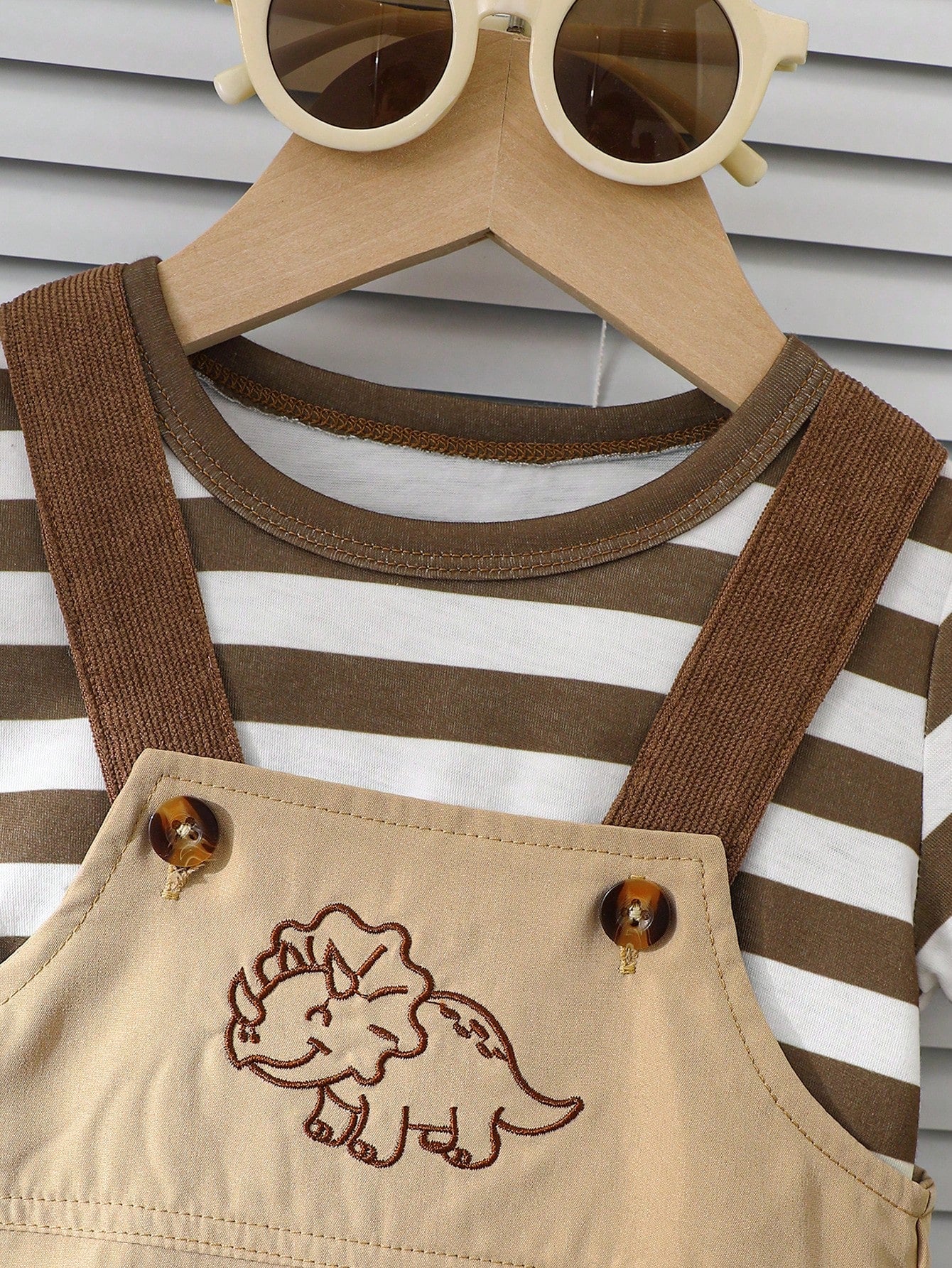 Prenda beige conjunto con overol para bebe y detalle de botones y camiseta a rayas