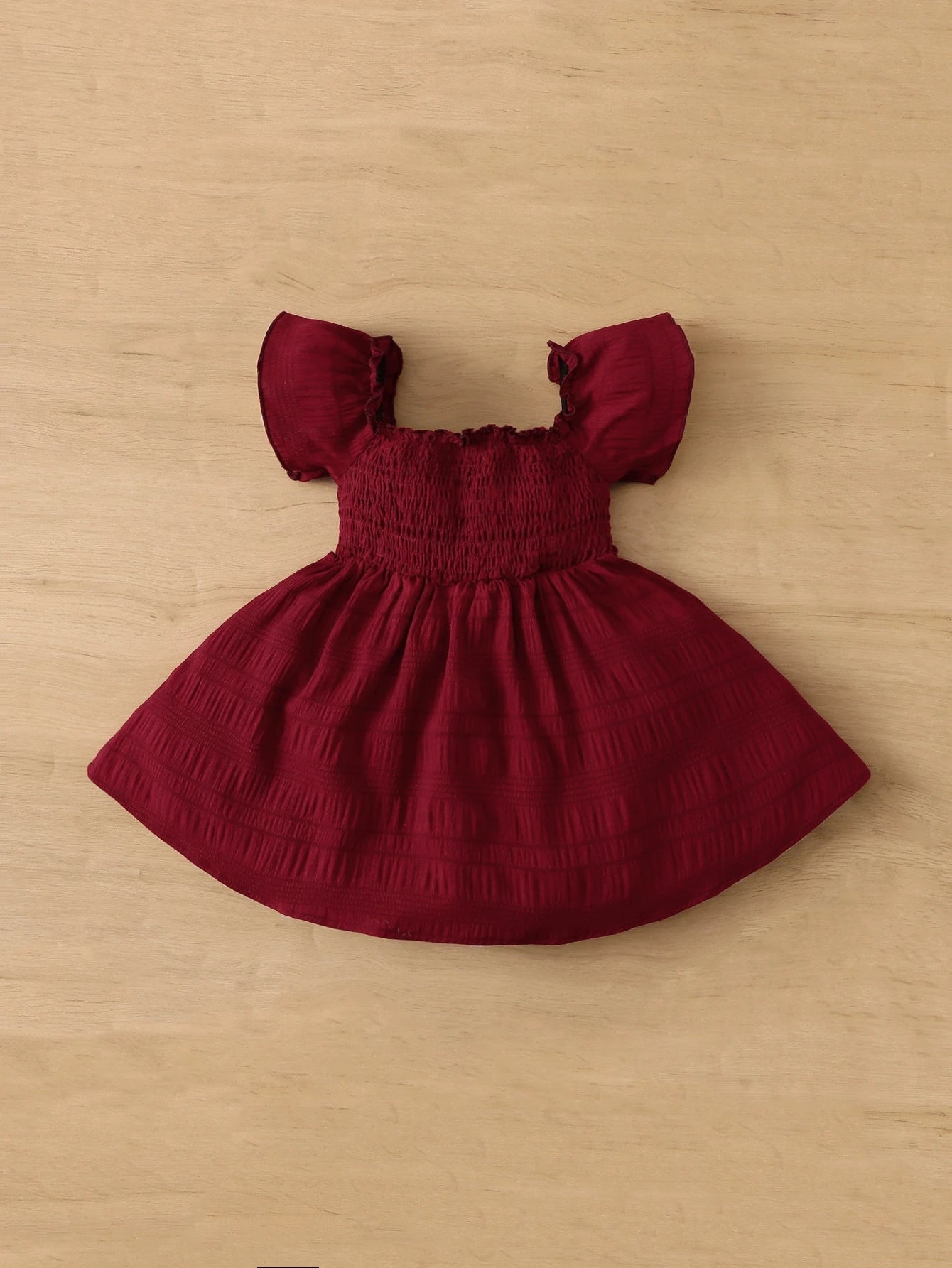 Prenda burdeos vestido para bebe detalle de la falda amplia y acabado texturizado