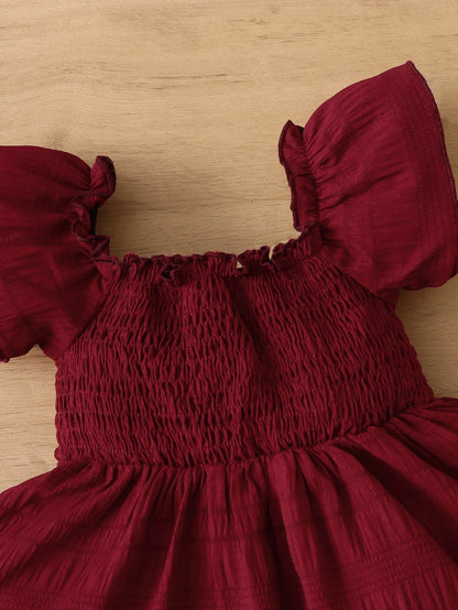 Prenda burdeos vestido para bebe vista completa con accesorios decorativos