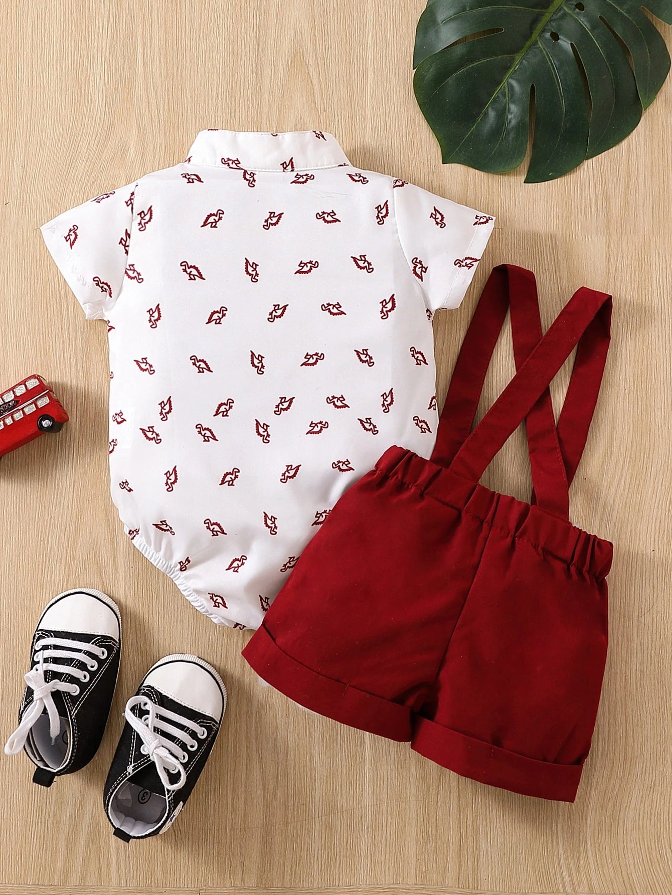 Prenda blanco body camisero para bebe con estampado de dinosaurios y shorts rojos vista trasera
