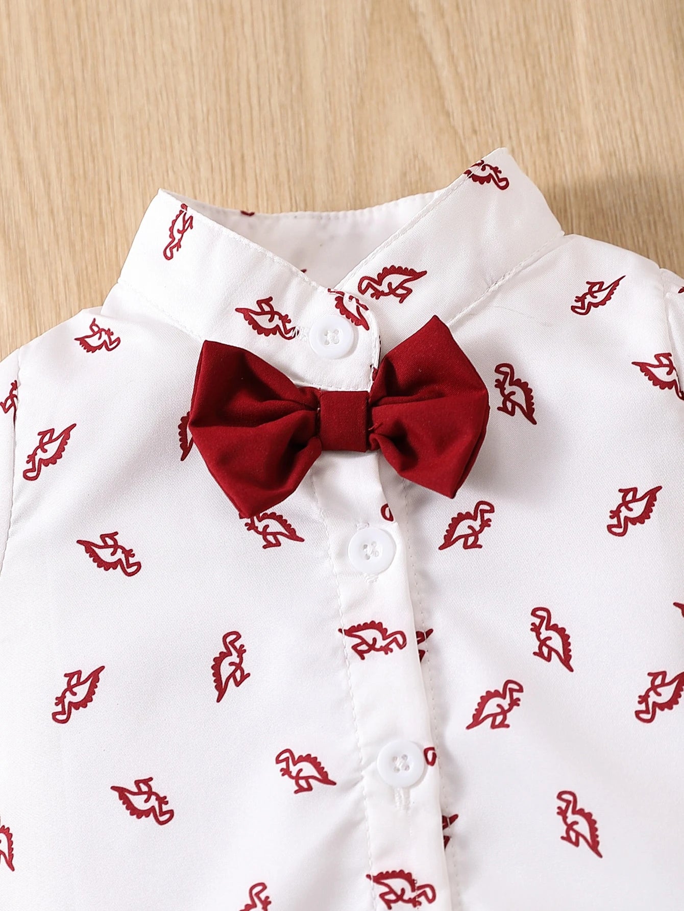 Prenda blanco body camisero para bebe con lazo rojo detalle frontal
