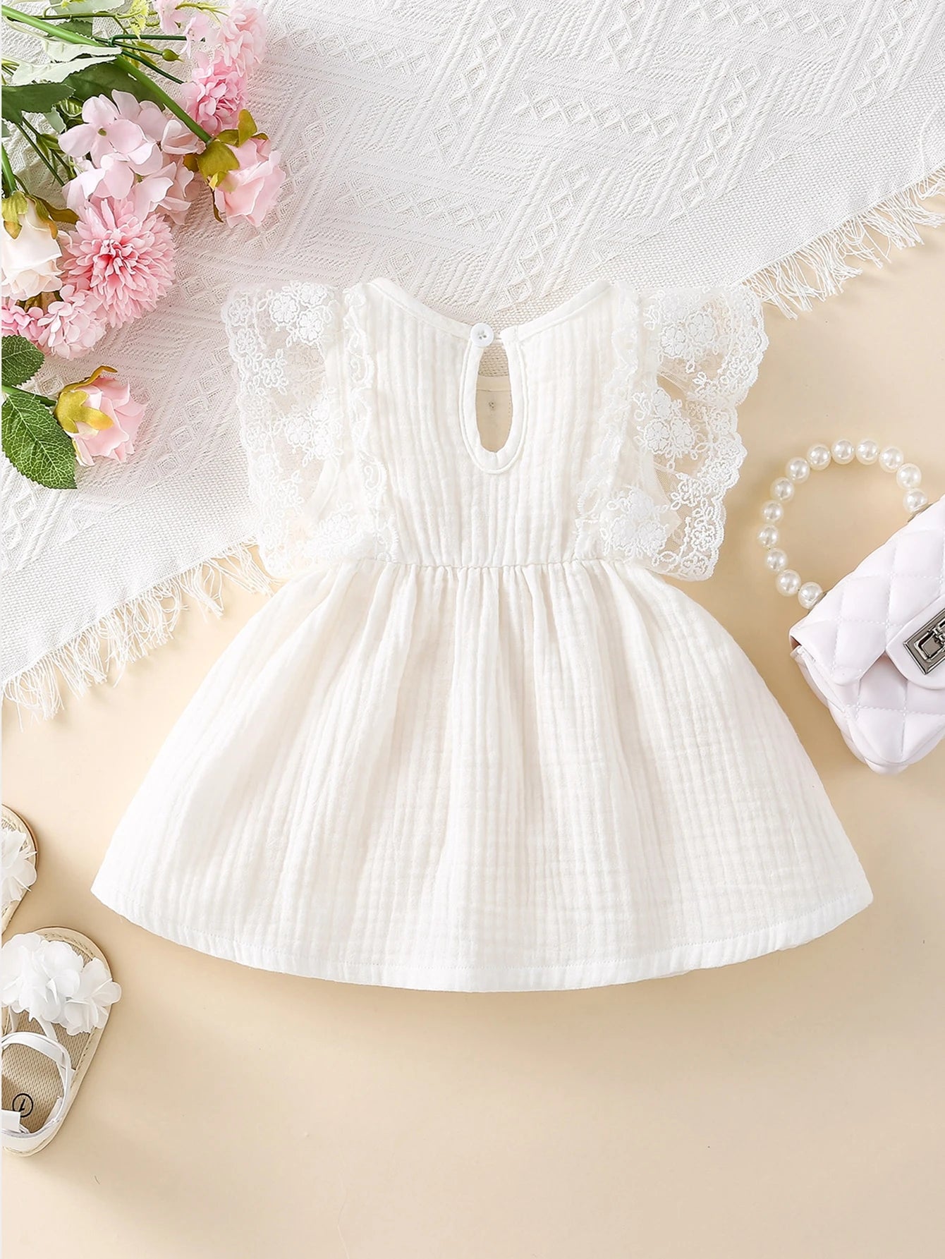 Prenda blanca vestido para bebe con detalle de botones y mangas de encaje