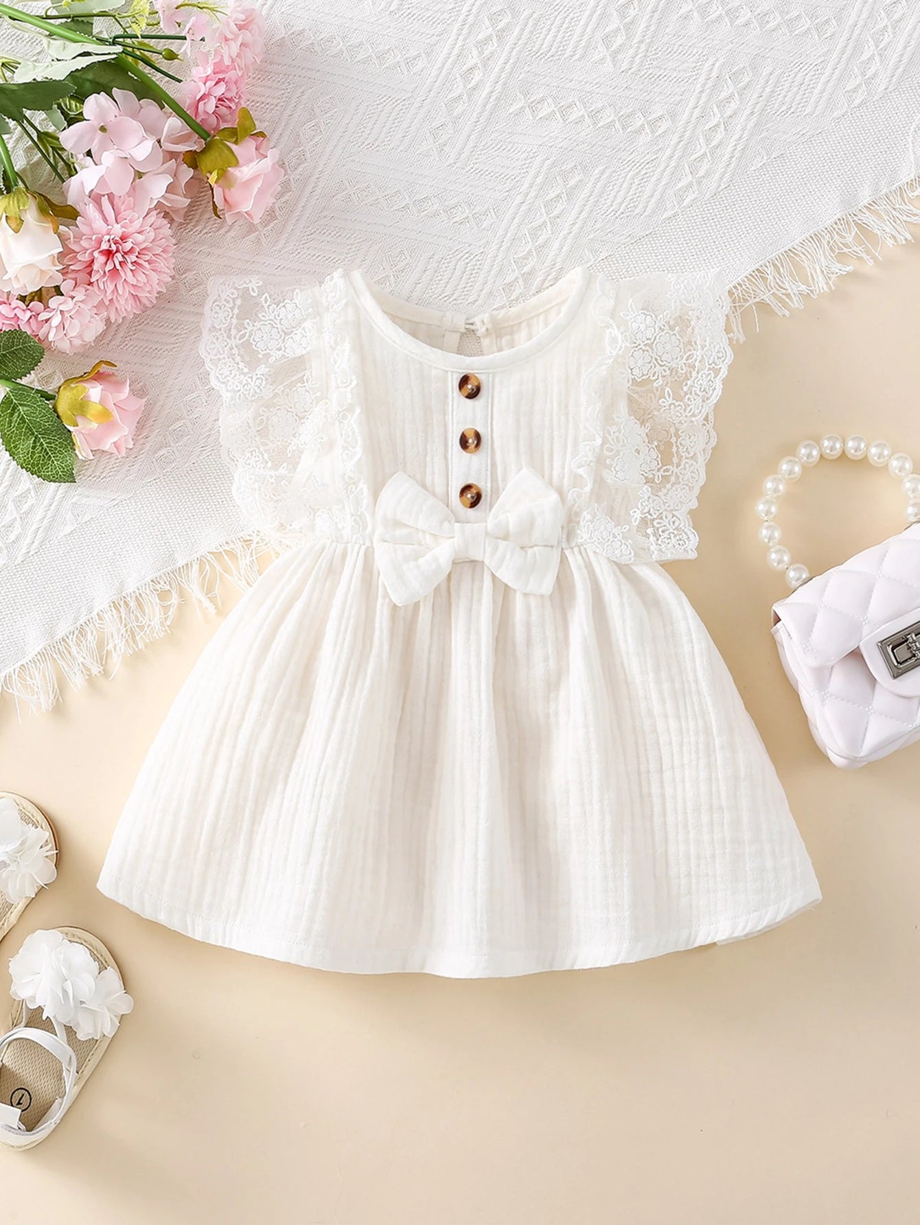 Prenda blanca vestido para bebe con detalle de lazo frontal y textura de algodón