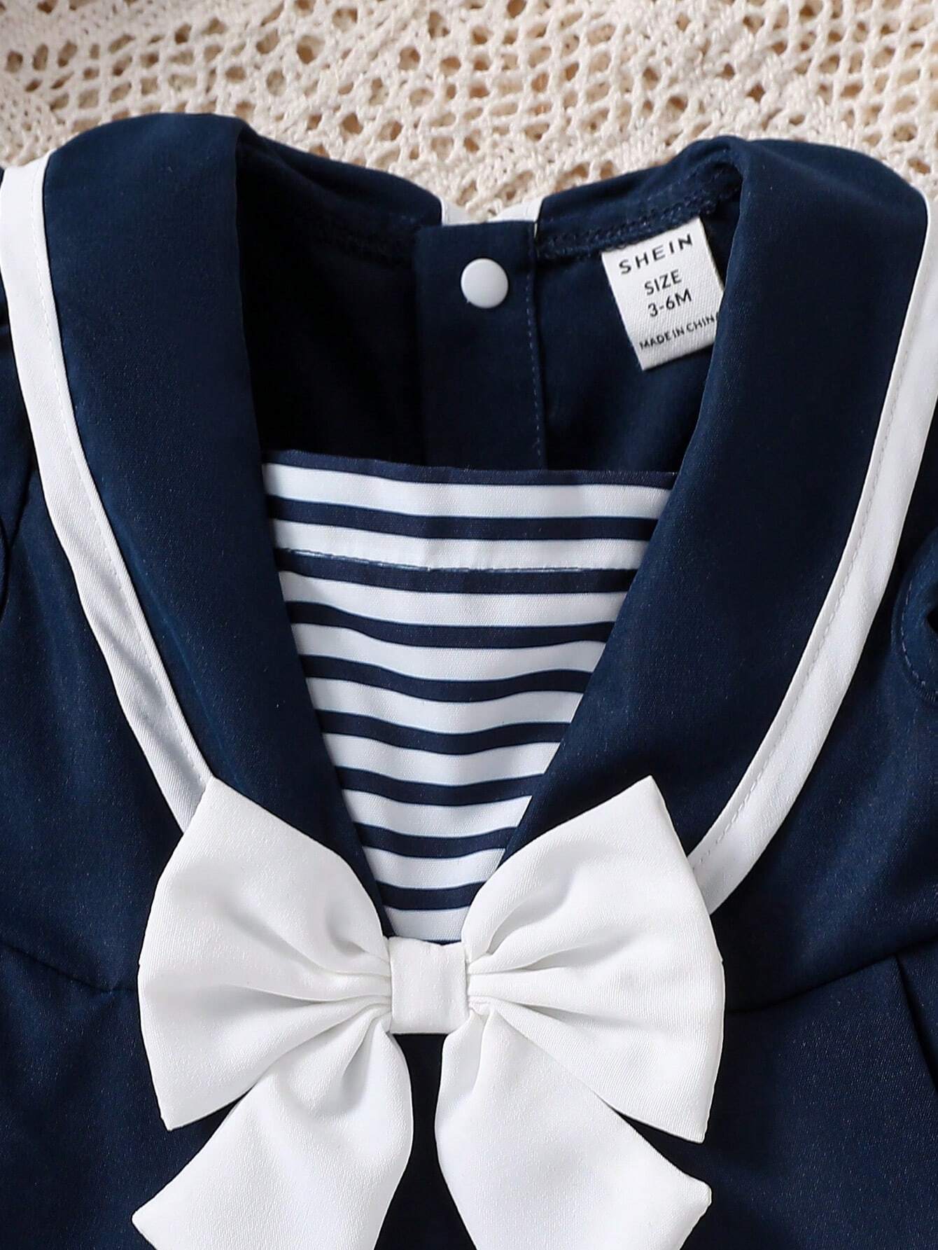 Prenda azul marino vestido para bebe con detalle de cuello marinero y lazo blanco