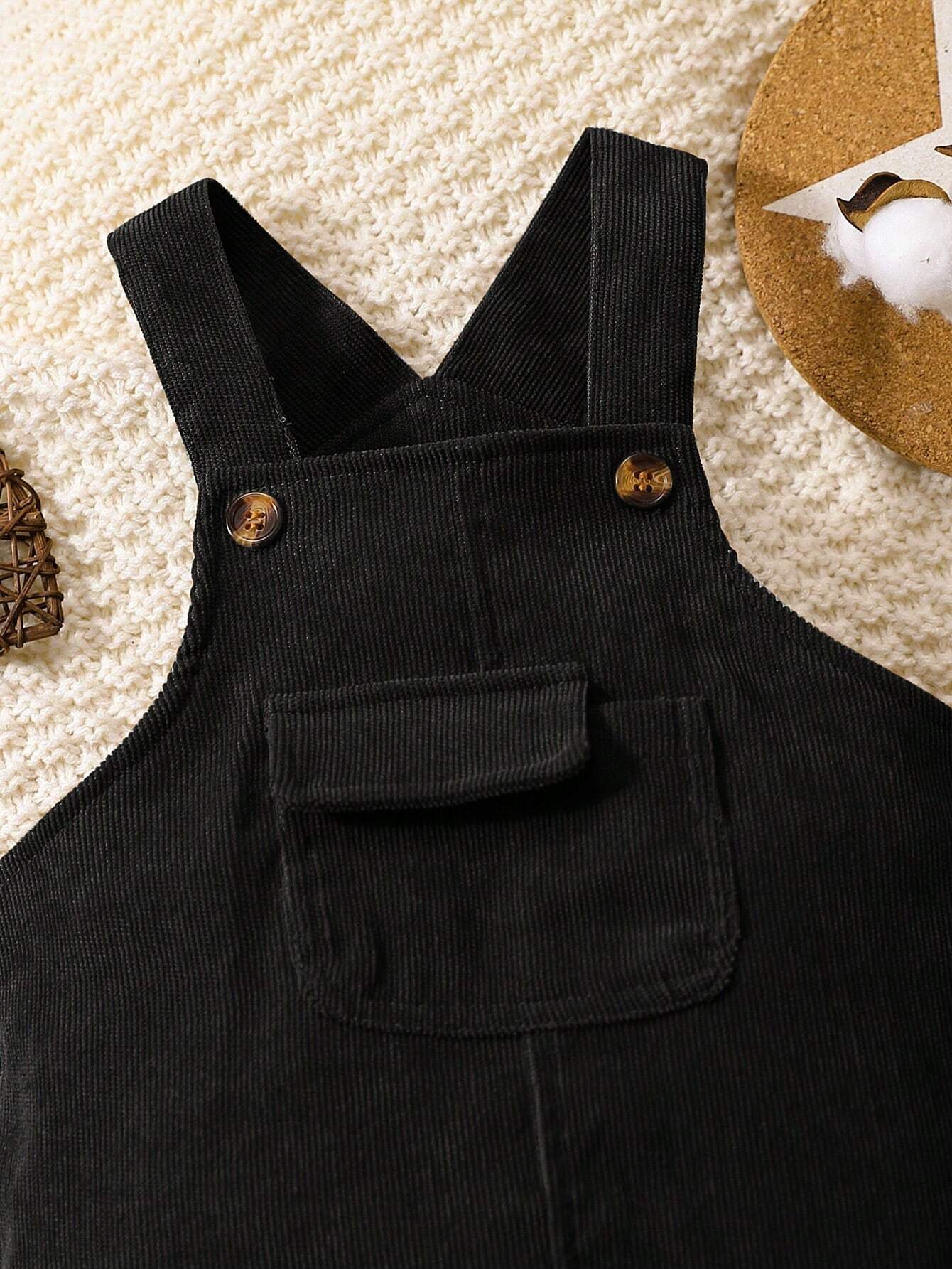Prenda negro overol para bebe detalle del bolsillo frontal con solapa