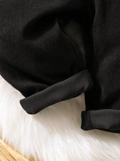 Prenda negro overol para bebe detalle de la tela de pana y bajos doblados