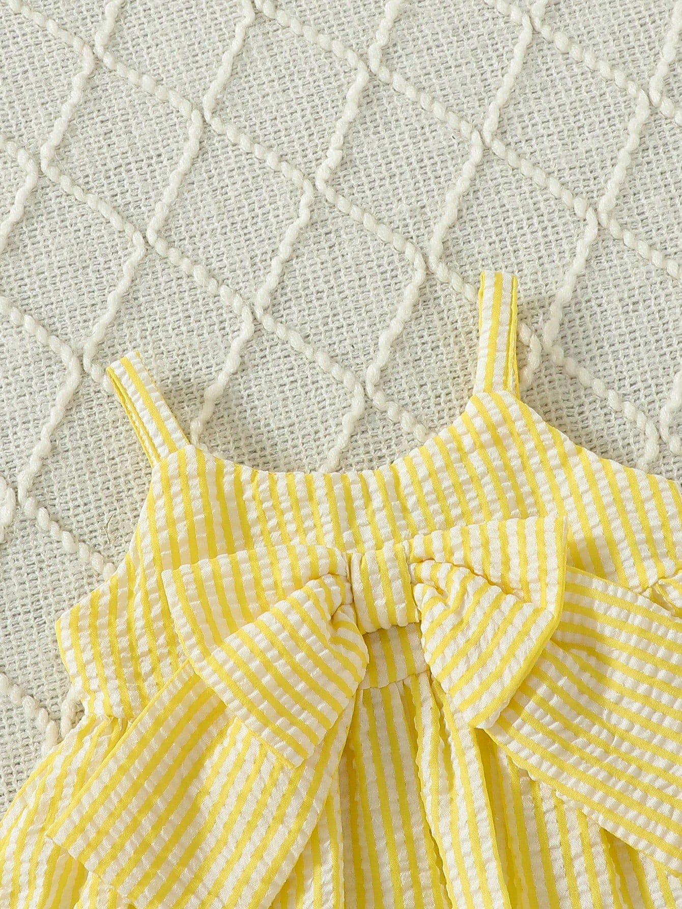 Prenda amarilla vestido a rayas para bebe con detalle de tirantes y lazo frontal