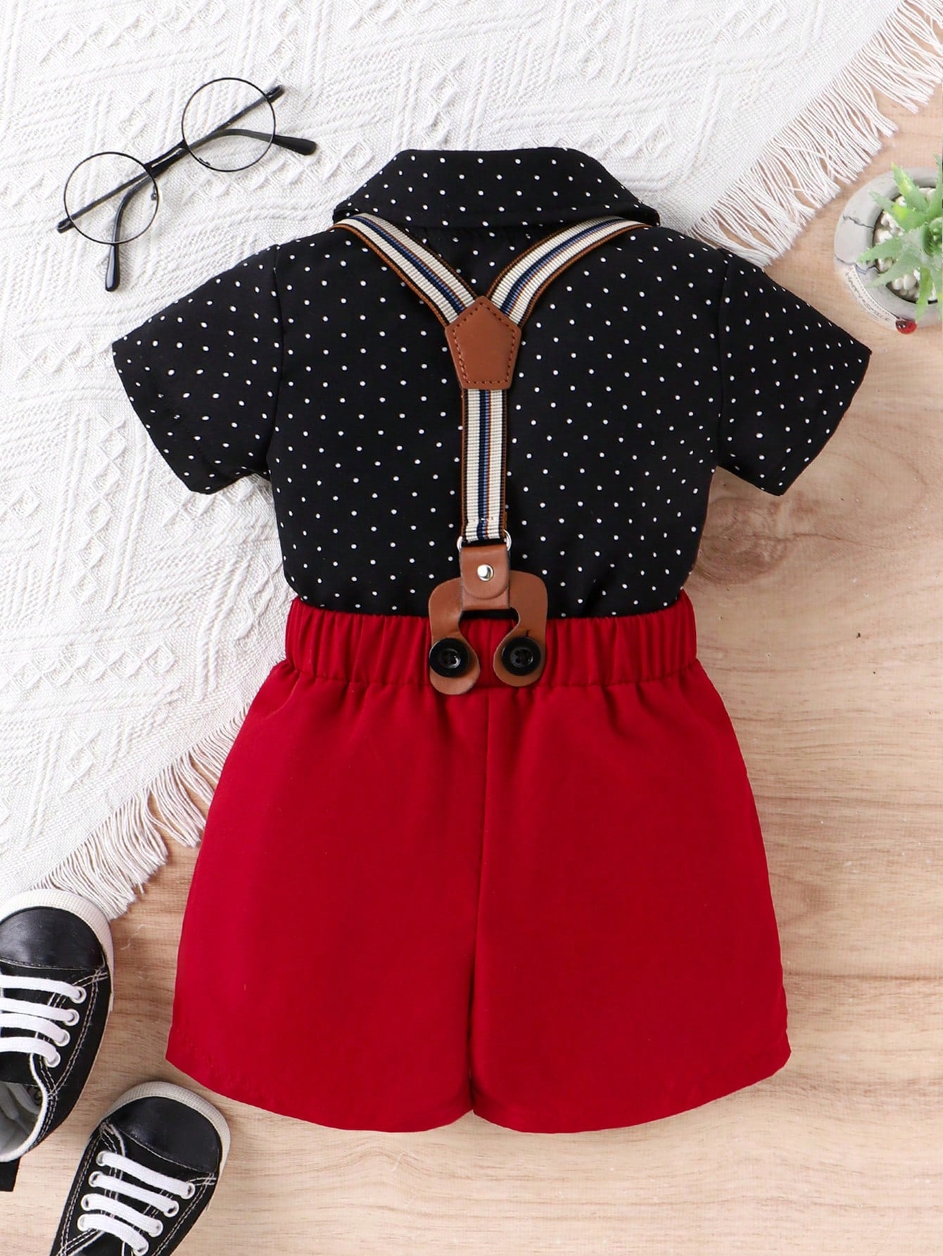 Prenda negra conjunto para bebe con lunares, moño rojo y tirantes vista frontal