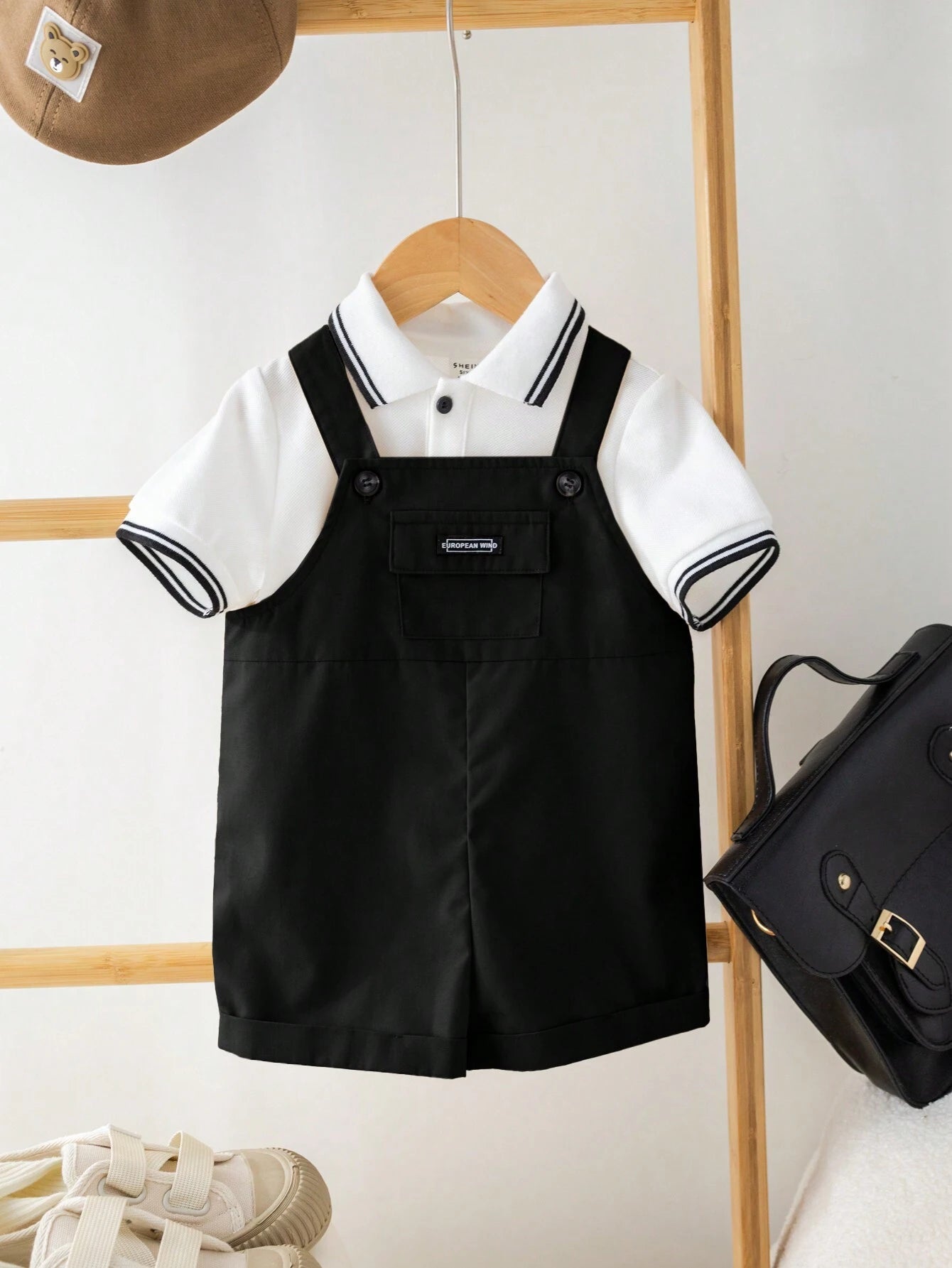 Prenda blanca y negra conjunto polo con overol para bebe modelado vista frontal