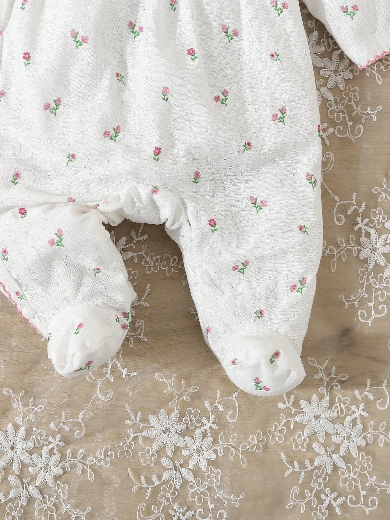 Prenda blanca pijama enterizo para bebe con flores detalle de piernas
