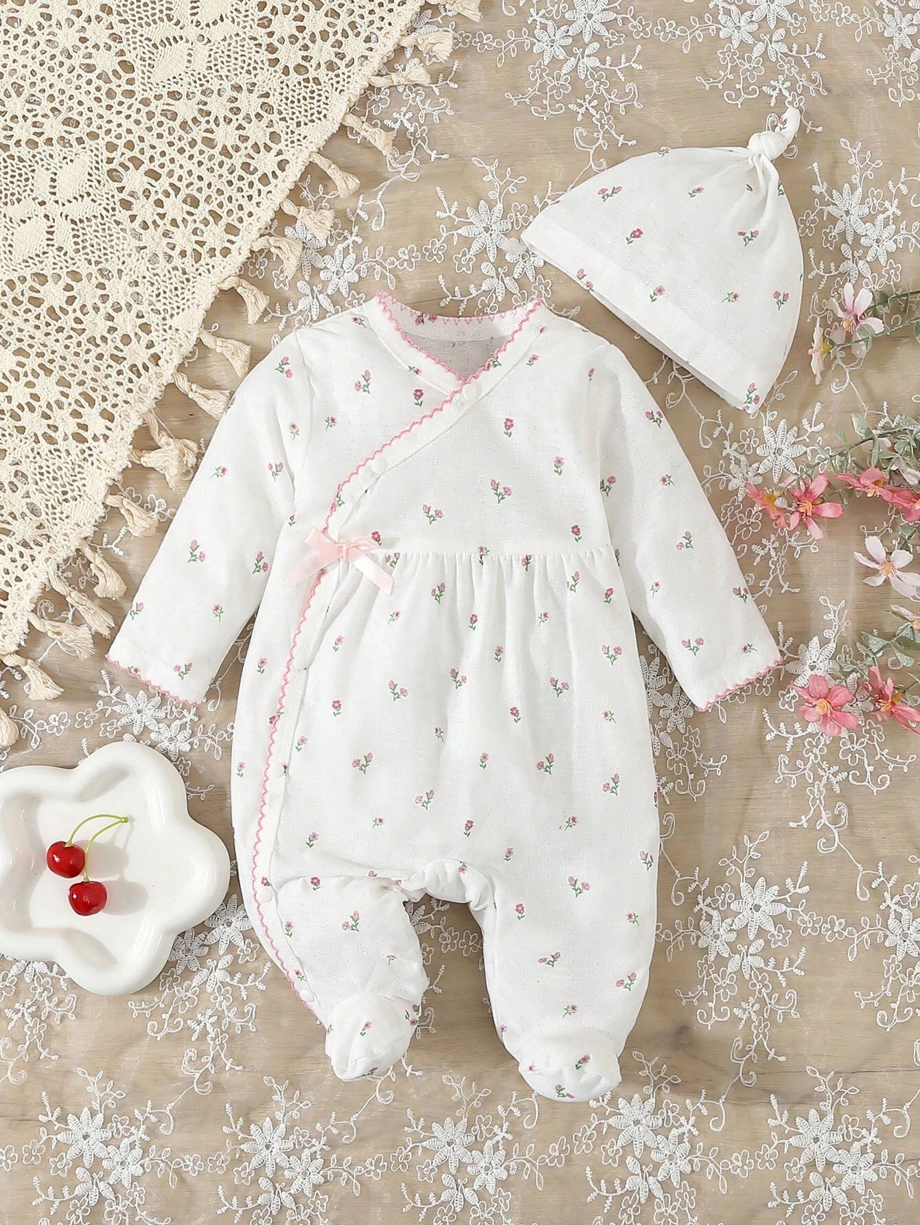 Prenda blanca pijama enterizo para bebe con flores y gorro vista frontal
