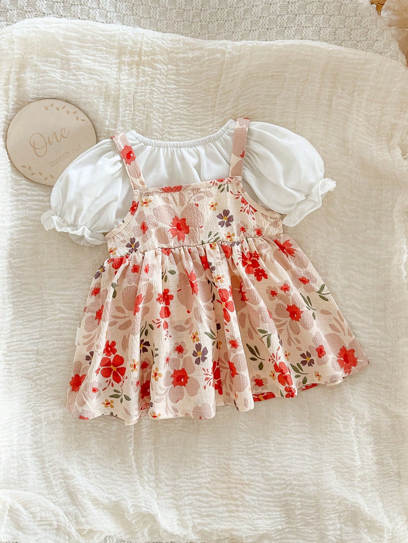 Prenda rosa conjunto floral para bebe sobre manta blanca