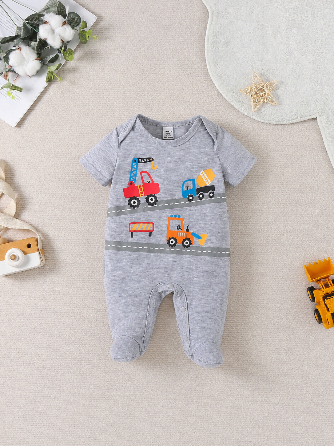 Prenda gris mameluco para bebe con estampado de construcción vista frontal