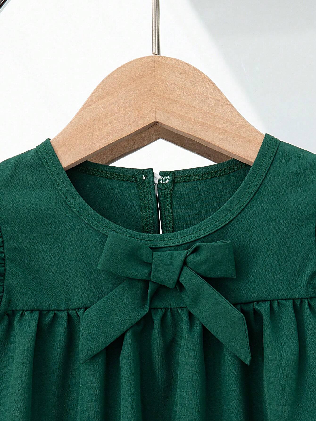 Vestido verde oscuro con moño delantero y mangas con volantes