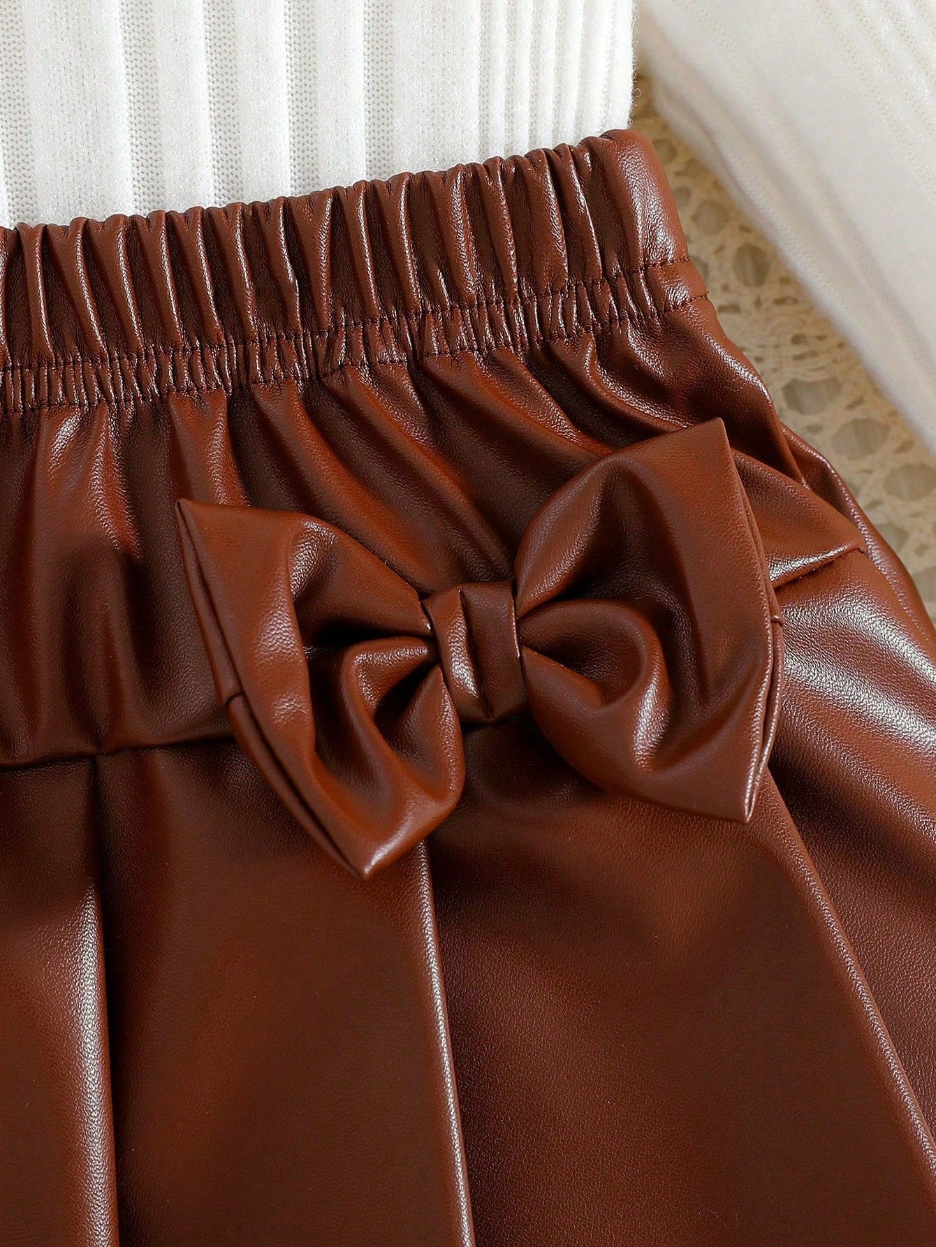 Prenda café falda plisada para bebe con lazos decorativos