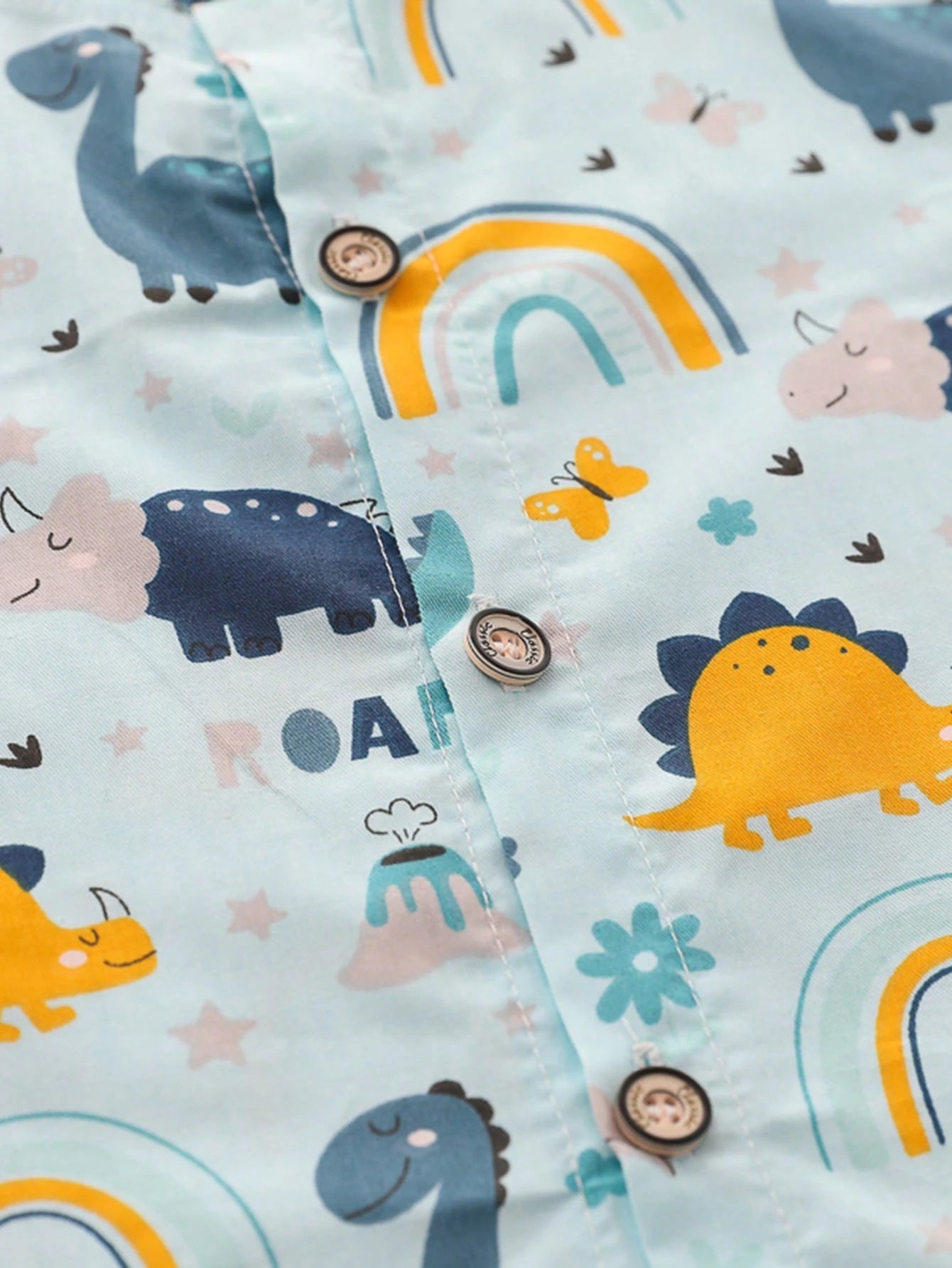 Prenda celeste camisa para bebe con estampado de dinosaurios detalle de botones
