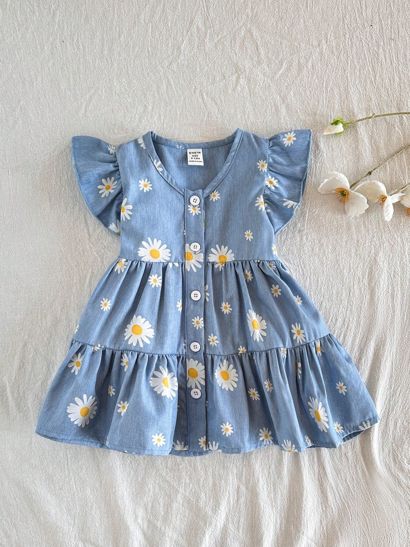Prenda azul vestido floral para bebe con margaritas y volantes vista frontal