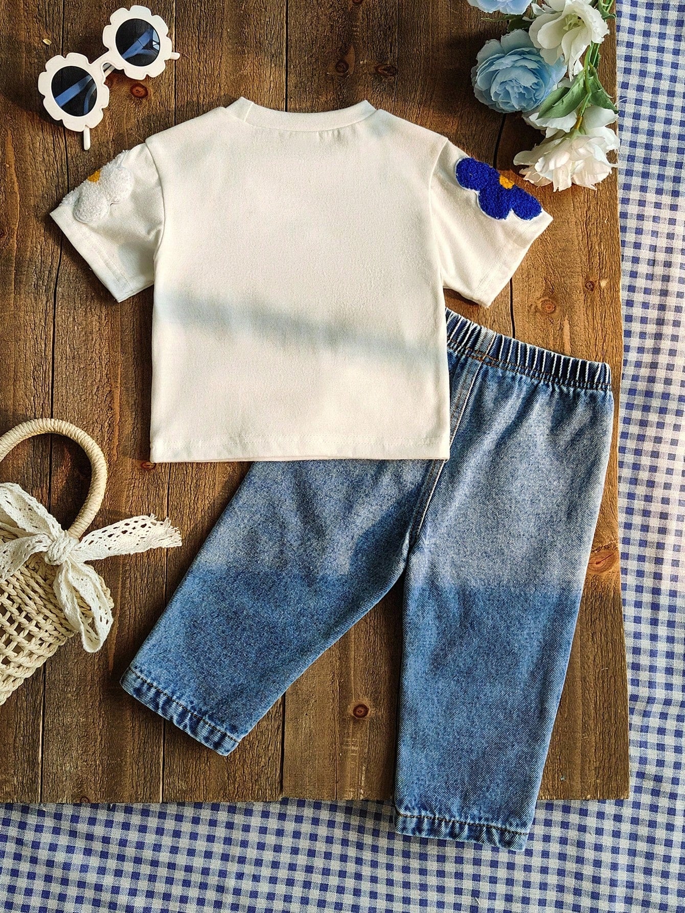 Prenda blanca conjunto para bebe con flores aplicadas y jean azul vista trasera
