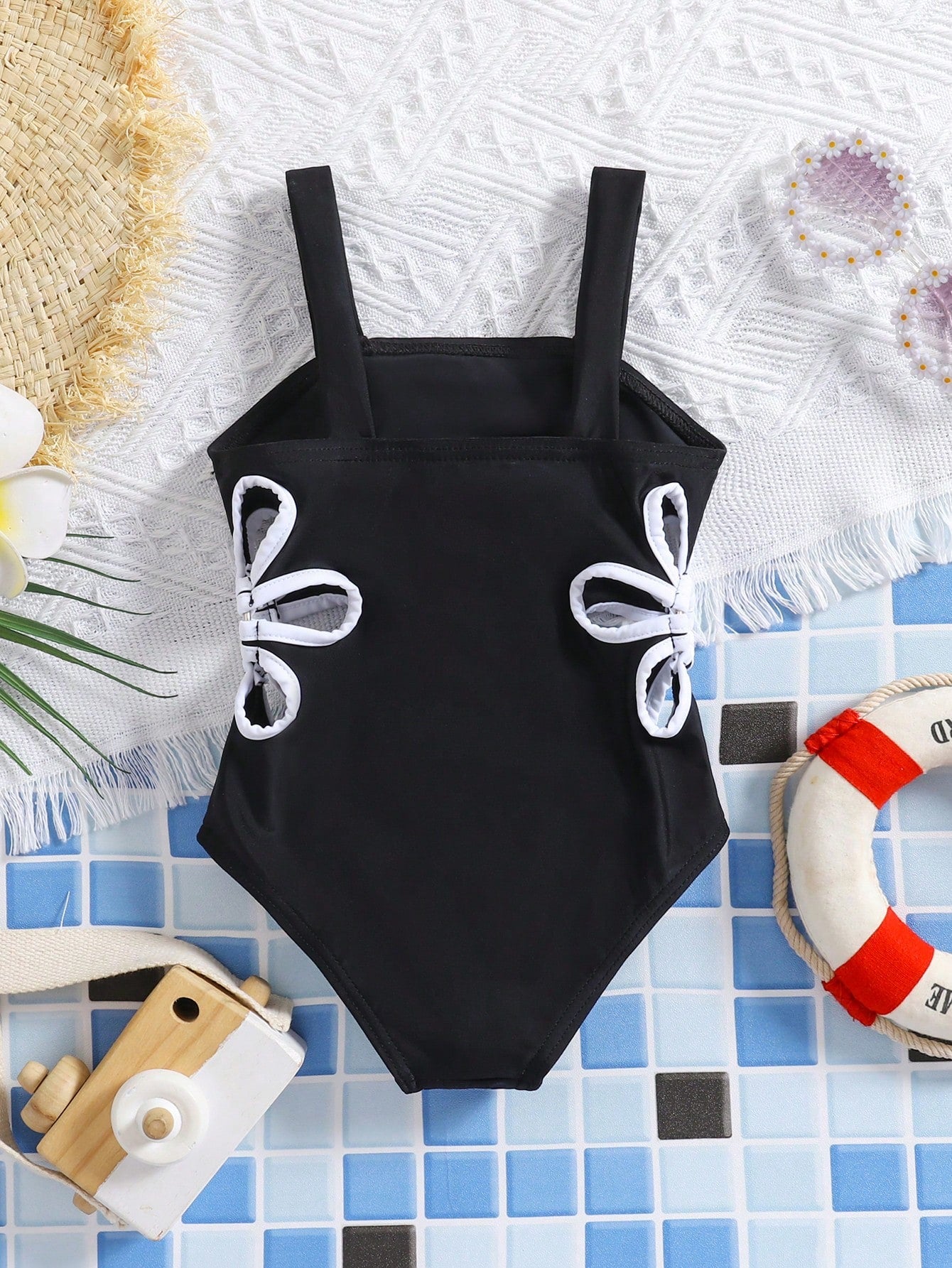 Prenda negra traje de baño para bebe con lazos laterales blancos vista trasera