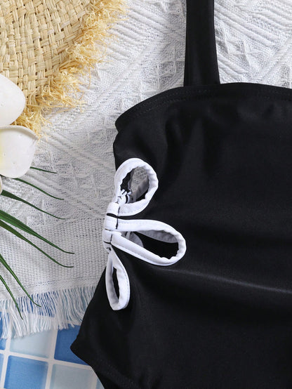 Prenda negra traje de baño para bebe con detalle de aberturas y lazos blancos