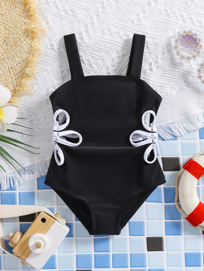 Prenda negra traje de baño para bebe con lazos laterales blancos vista frontal