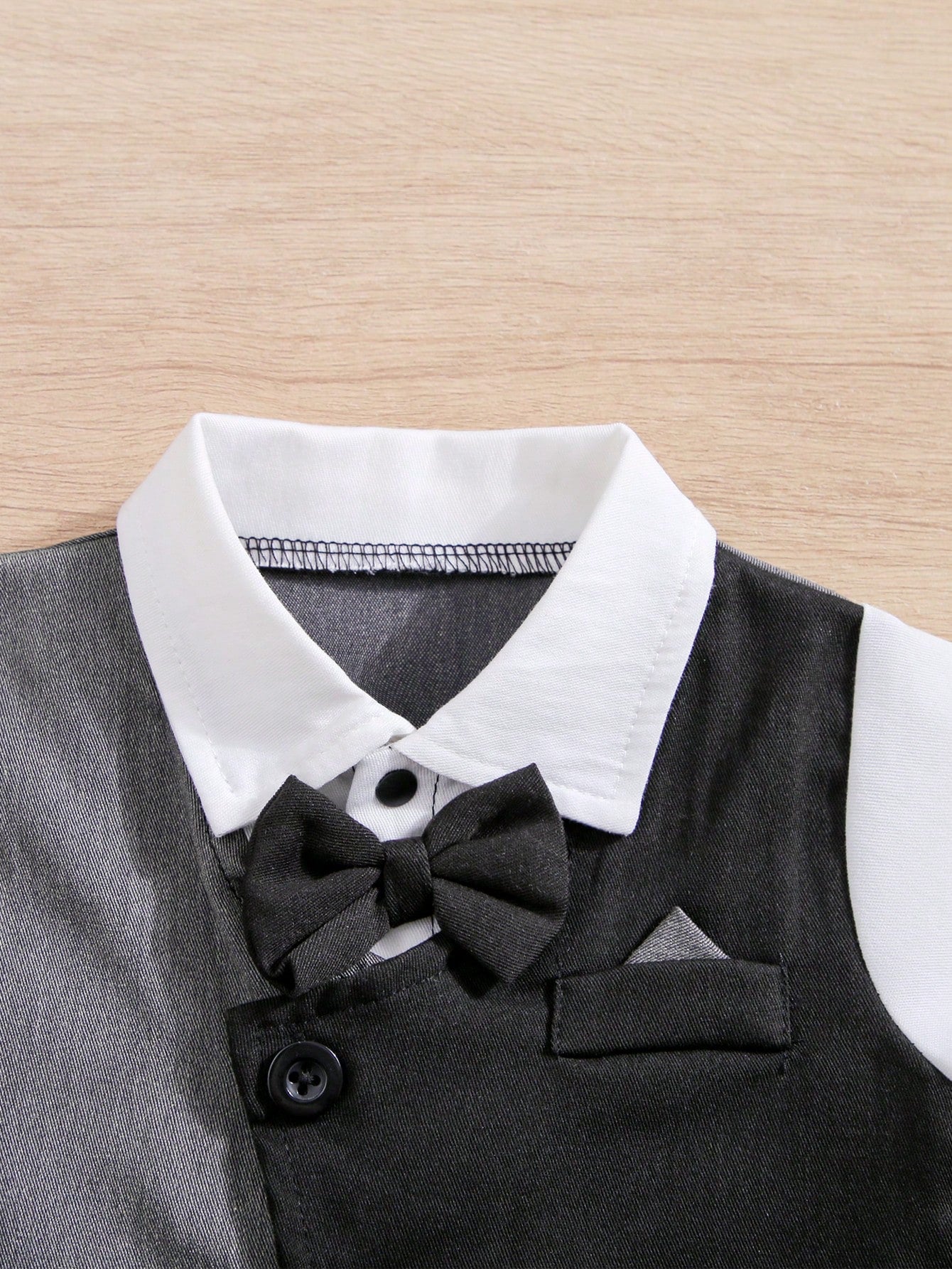 Prenda negro enterizo elegante para bebe con detalle de corbatín

