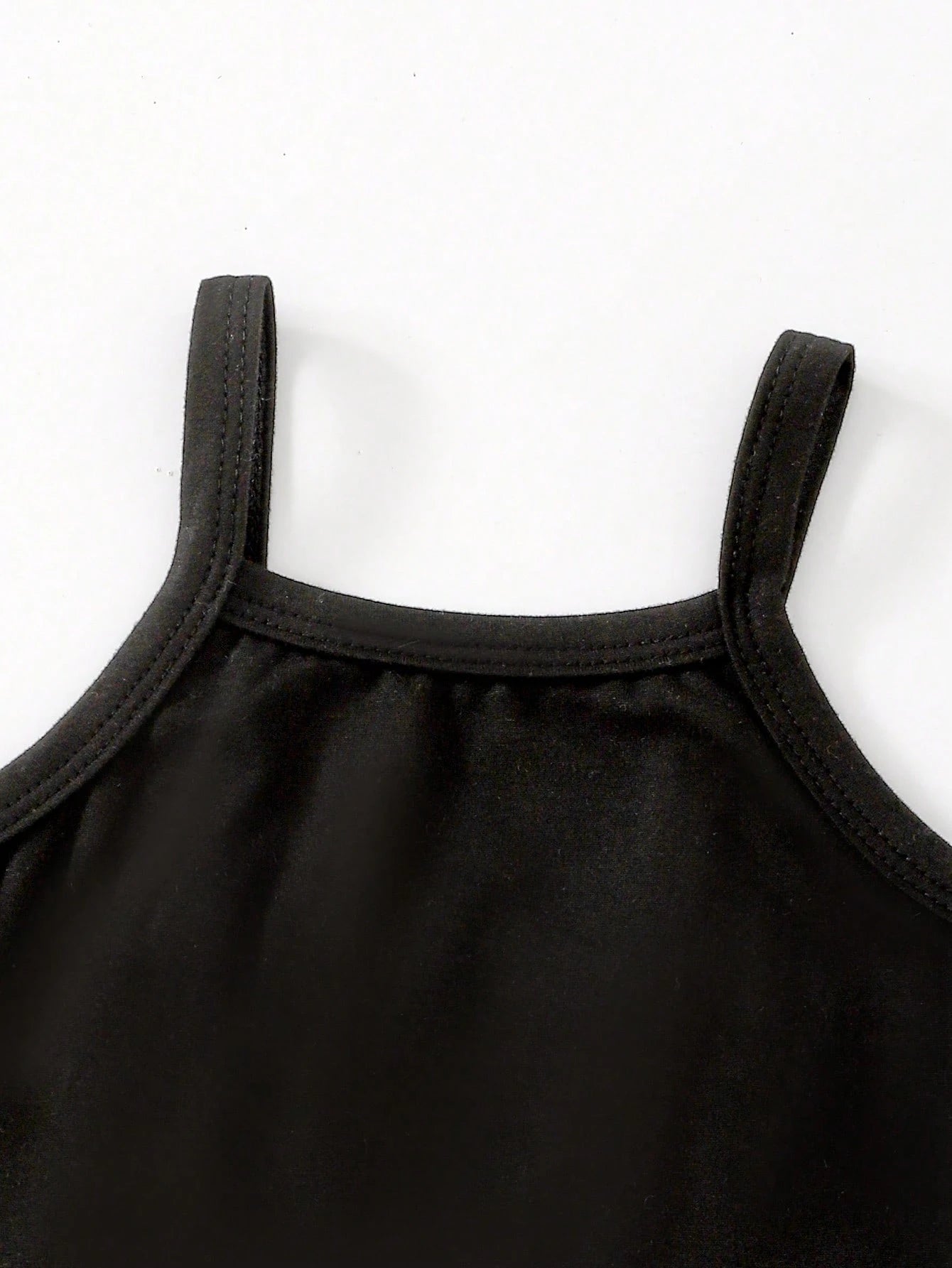 Prenda negra top para bebe con tirantes y costuras reforzadas detalle del acabado