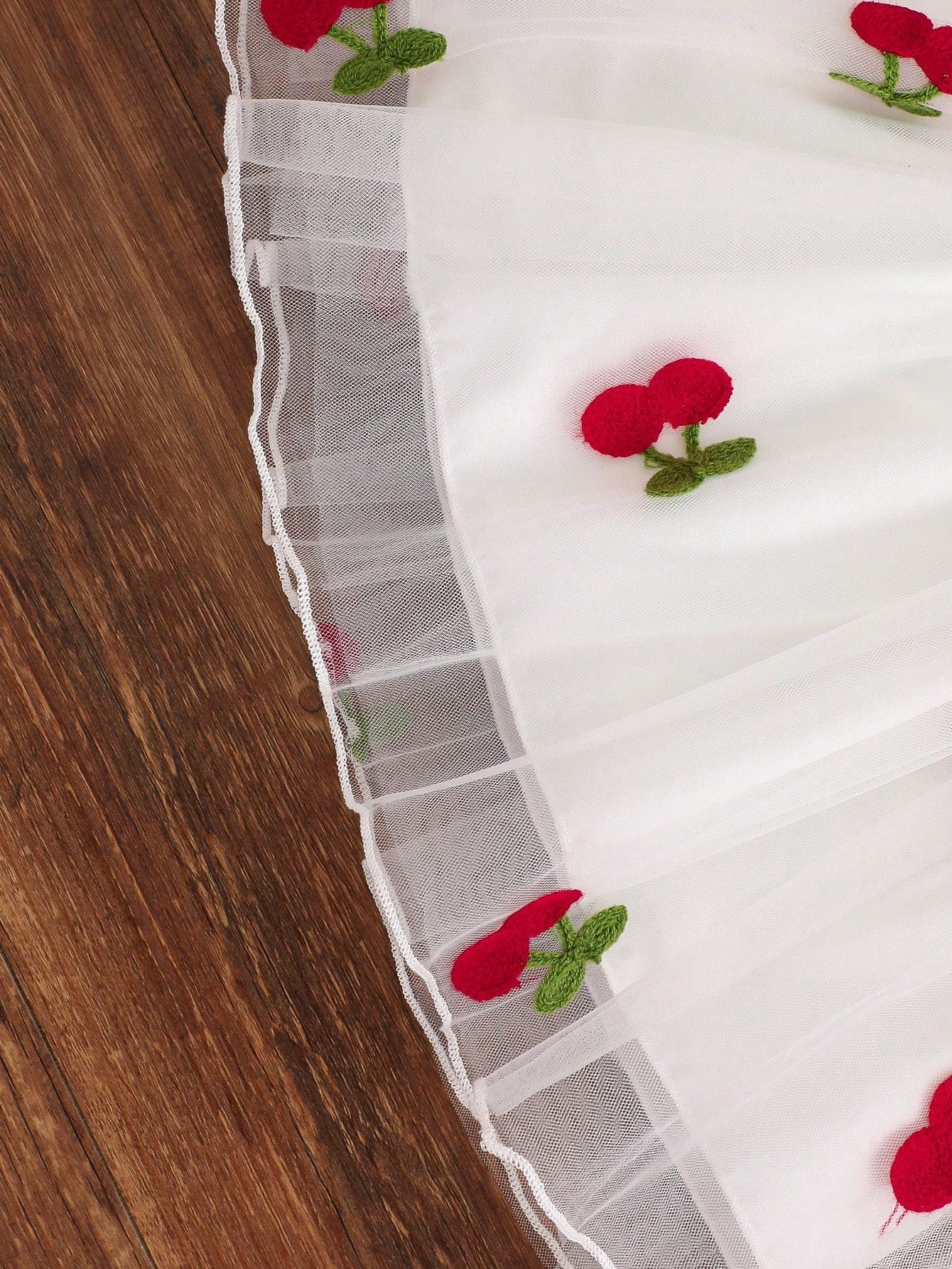 Prenda blanca vestido para bebe de malla con cerezas bordadas detalle del acabado