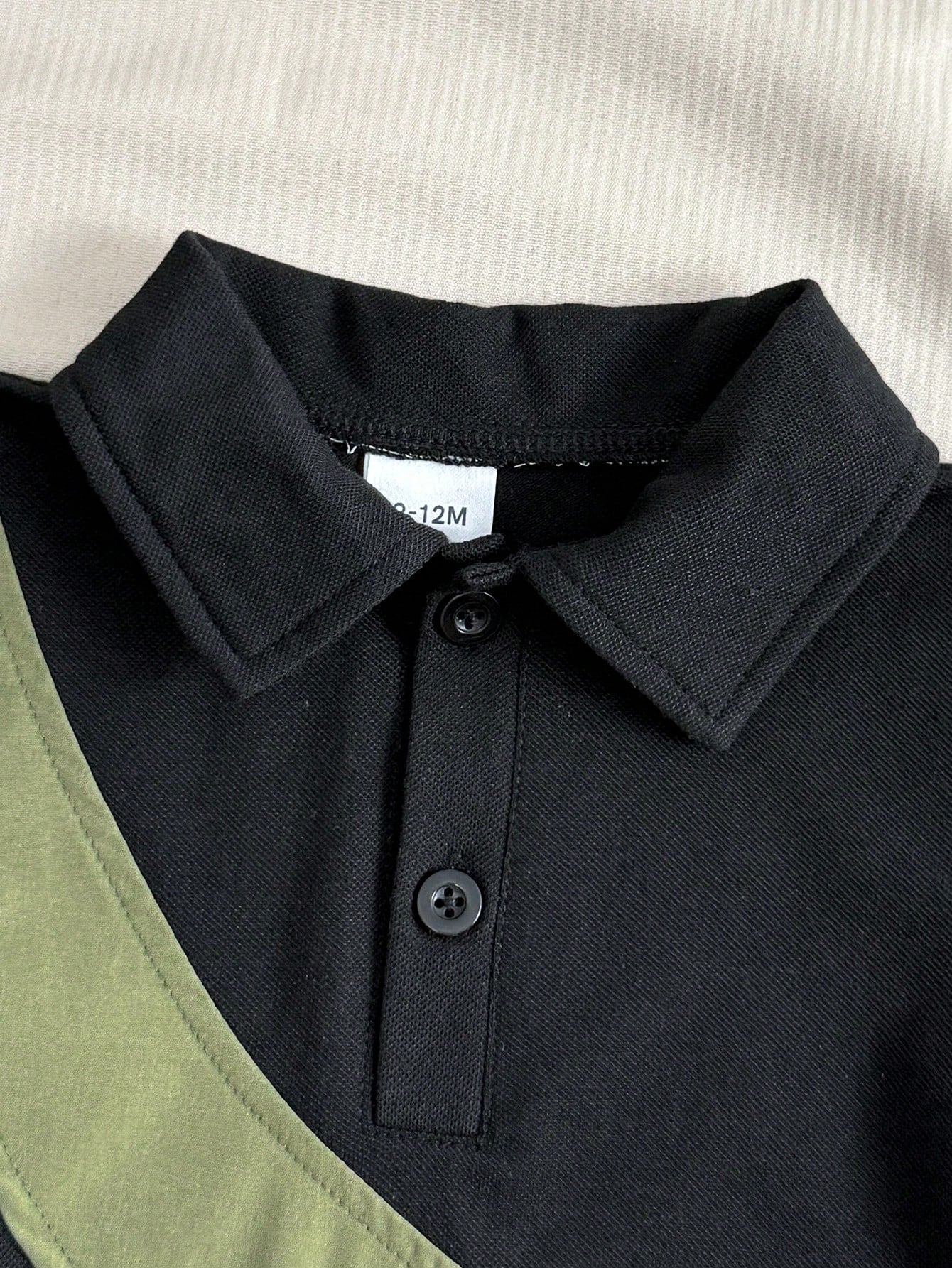 Prenda negra camisa polo para bebe con detalle de cuello y botones
