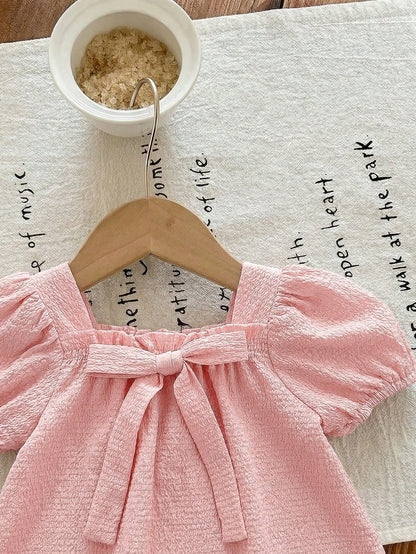 Prenda rosa pálido vestido para bebe con lazo frontal detalle del acabado