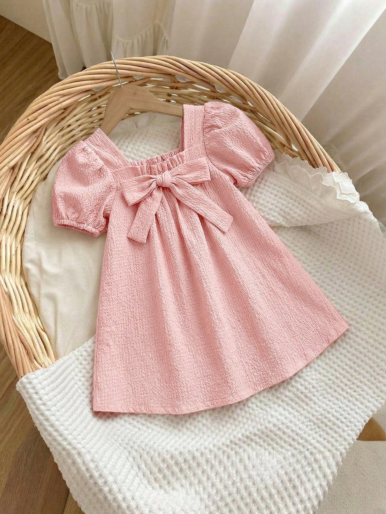 Prenda rosa pálido vestido para bebe con lazo frontal vista frontal