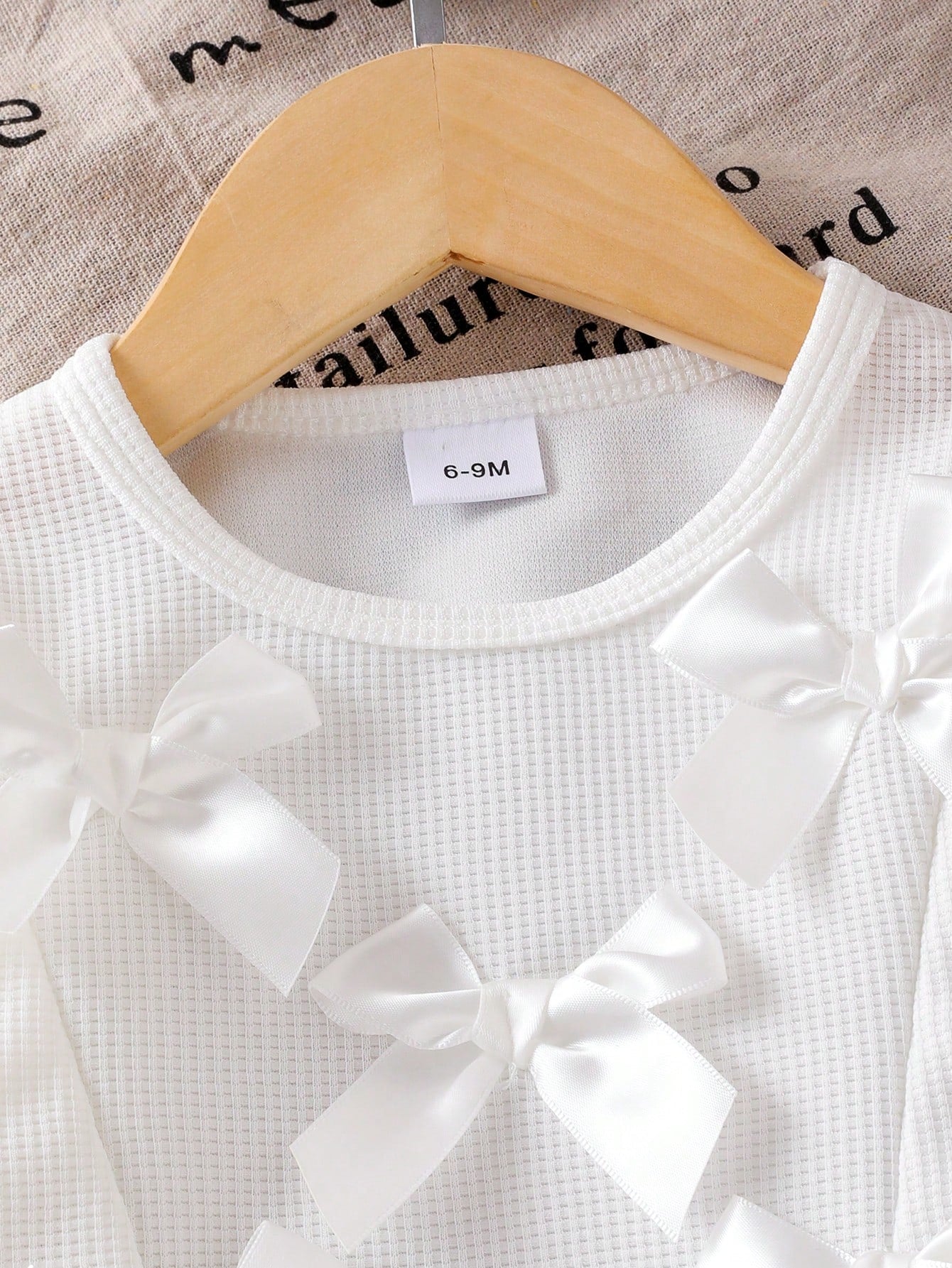 Prenda blanca conjunto para bebe con detalle de lazos 3D en la blusa
