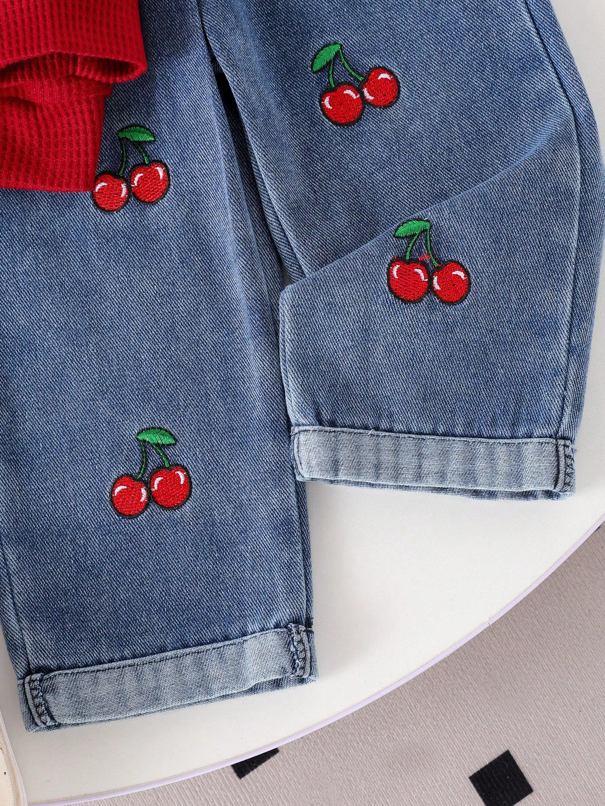 Pantalón de mezclilla azul para bebe con detalle de cerezas bordadas y ruedos doblados