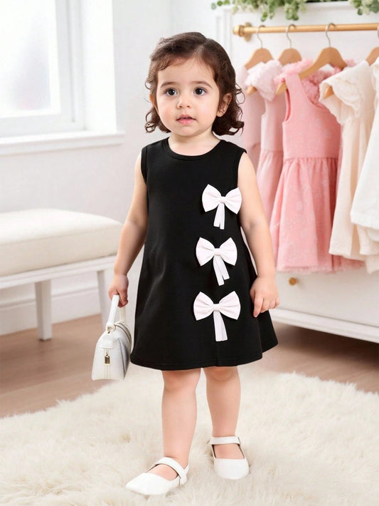 Prenda negro vestido para bebe con lazos blancos vista frontal
