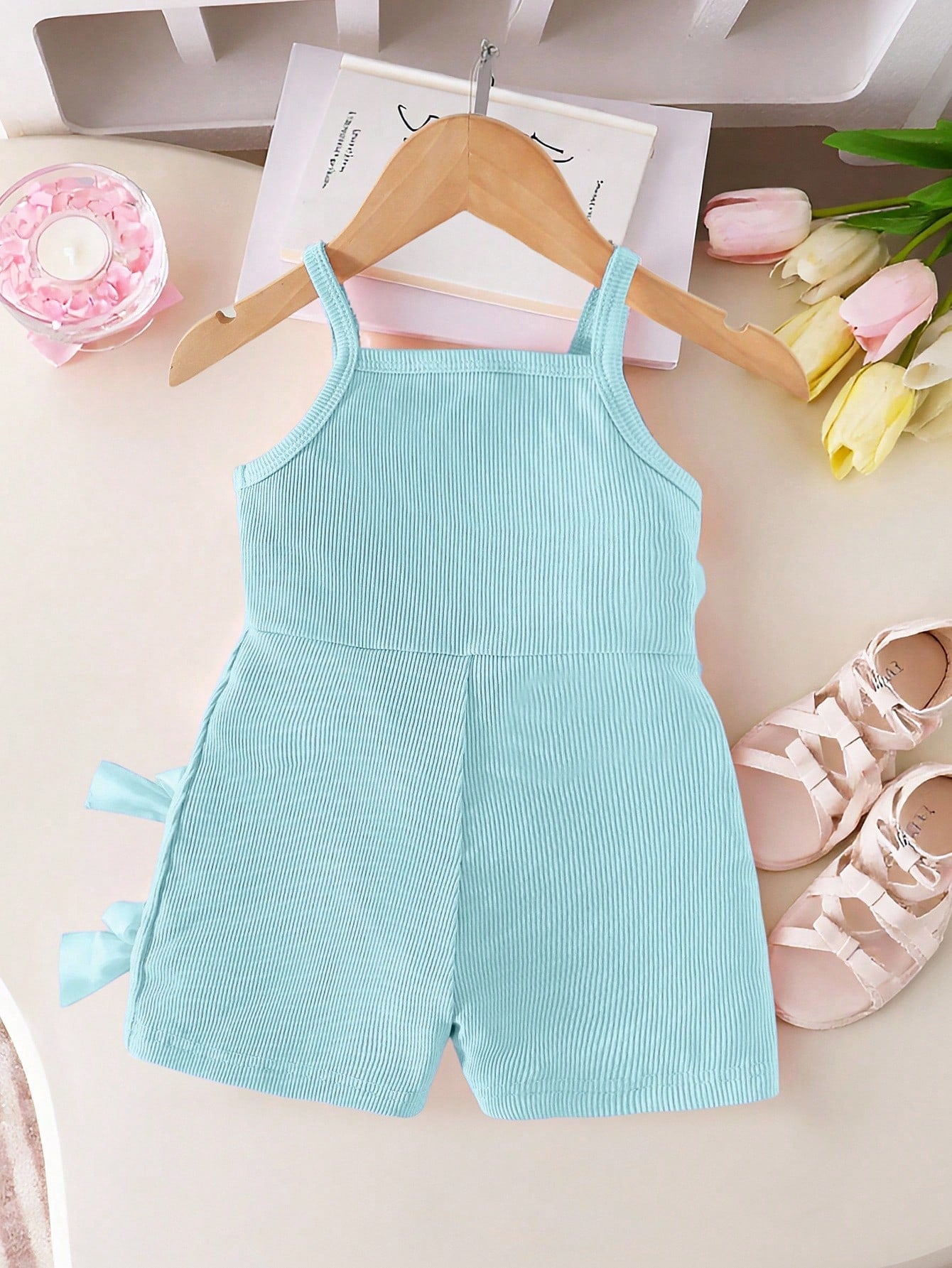 Prenda azul claro pelele para bebe con lazos decorativos vista trasera
