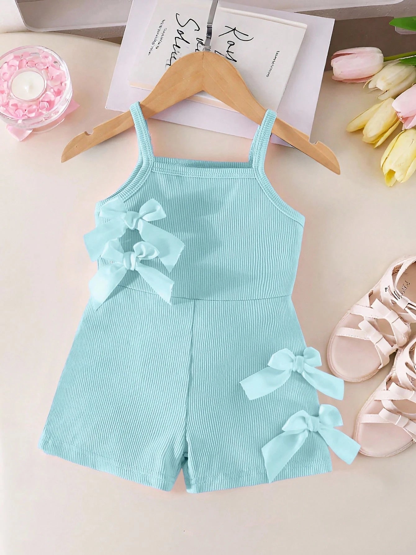 Prenda azul claro pelele para bebe con lazos decorativos vista frontal
