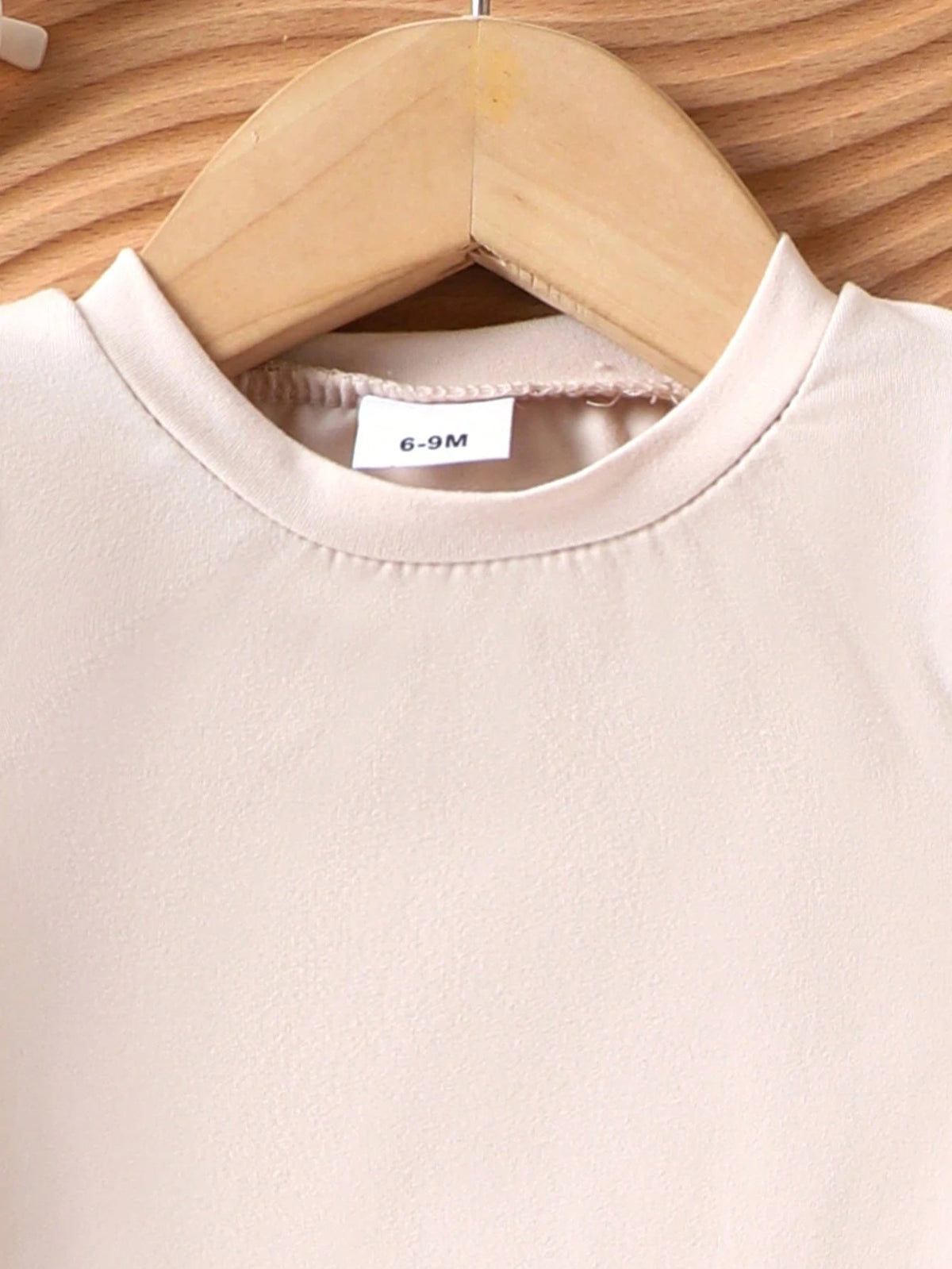 Prenda beige blusa para bebe detalle de cuello redondo y manga larga