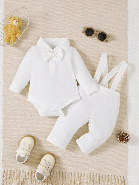 Conjunto blanco para bebé con pelele de manga larga, moño y pantalón con tirantes, vista frontal.