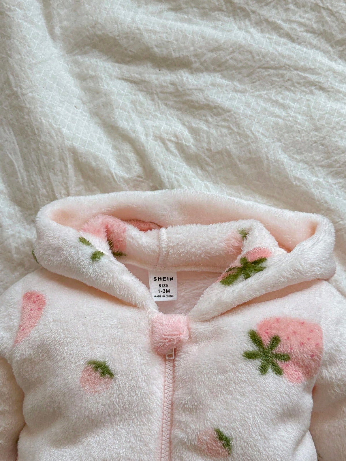 Mameluco rosa para bebe con detalle de capucha y cremallera frontal