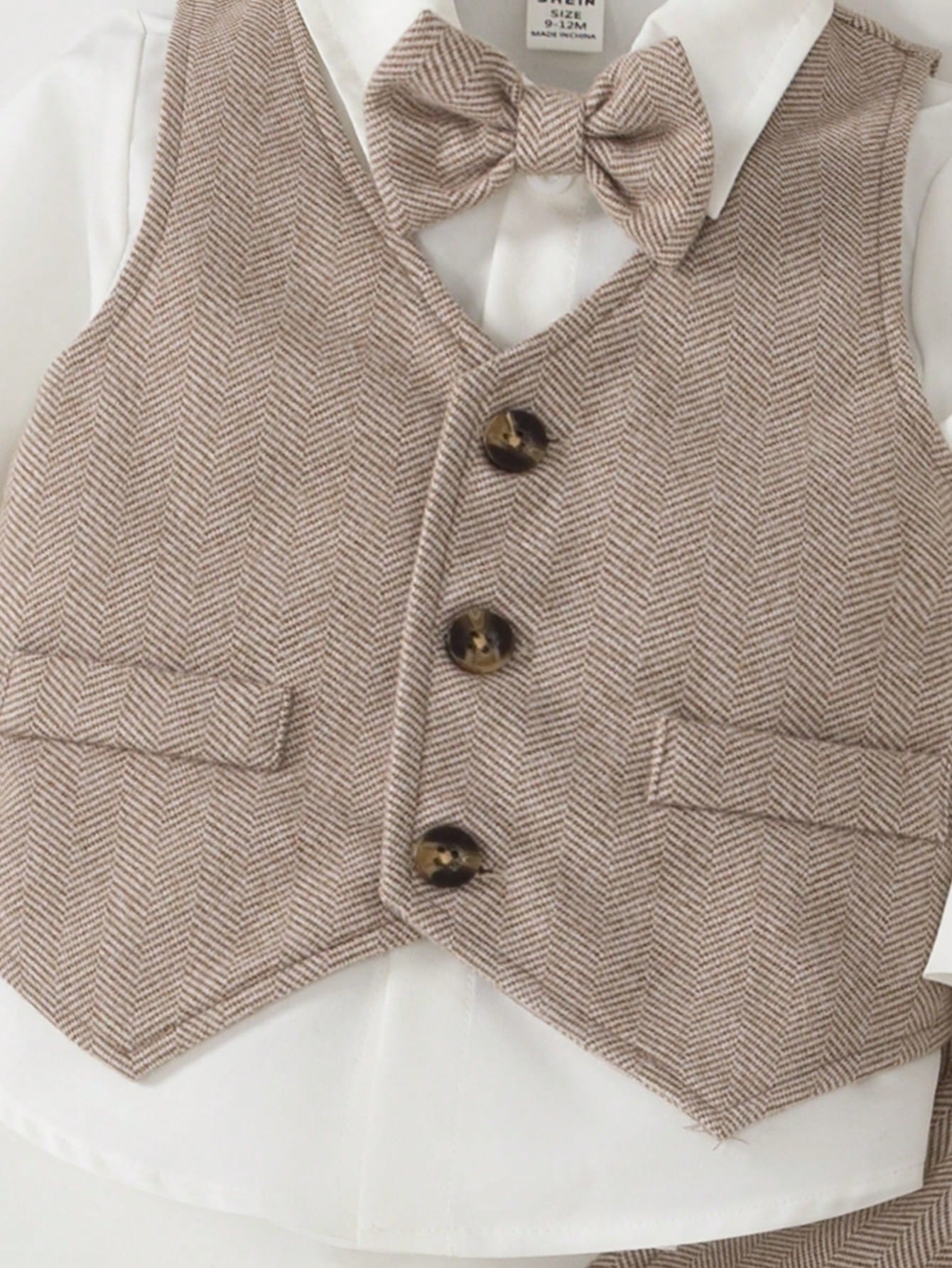 Prenda beige conjunto para bebe con detalle de chaleco tipo espiga y botones