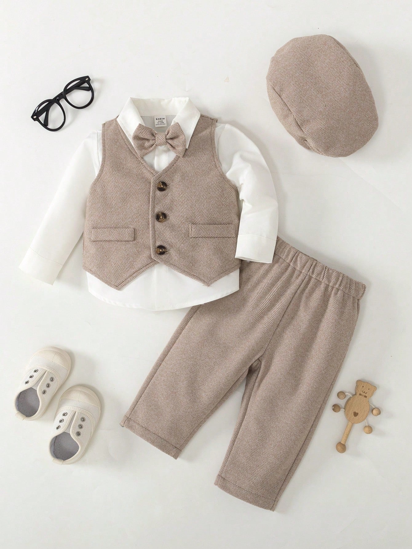 Prenda beige conjunto para bebe con chaleco pantalón moño y gorra vista frontal