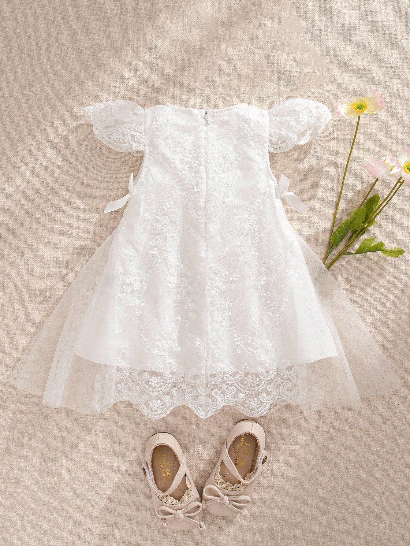 Prenda blanca vestido de tul bordado para bebe vista trasera con lazos
