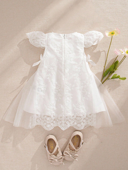 Prenda blanca vestido de tul bordado para bebe vista trasera con lazos
