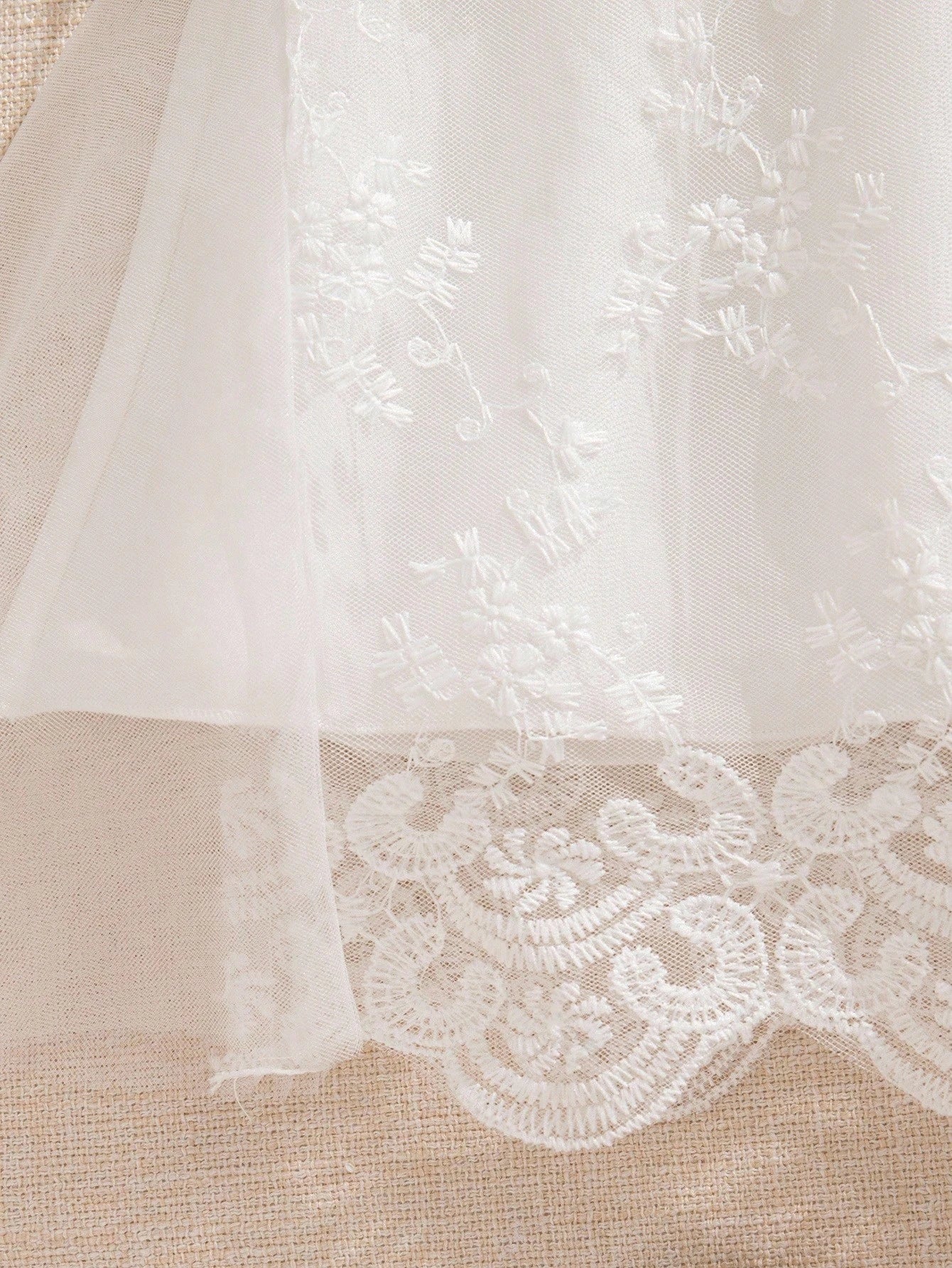 Prenda blanca vestido de tul bordado para bebe detalle de encaje inferior