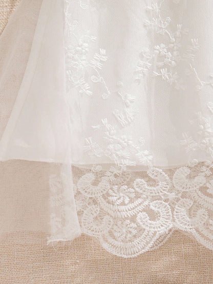Prenda blanca vestido de tul bordado para bebe detalle de encaje inferior